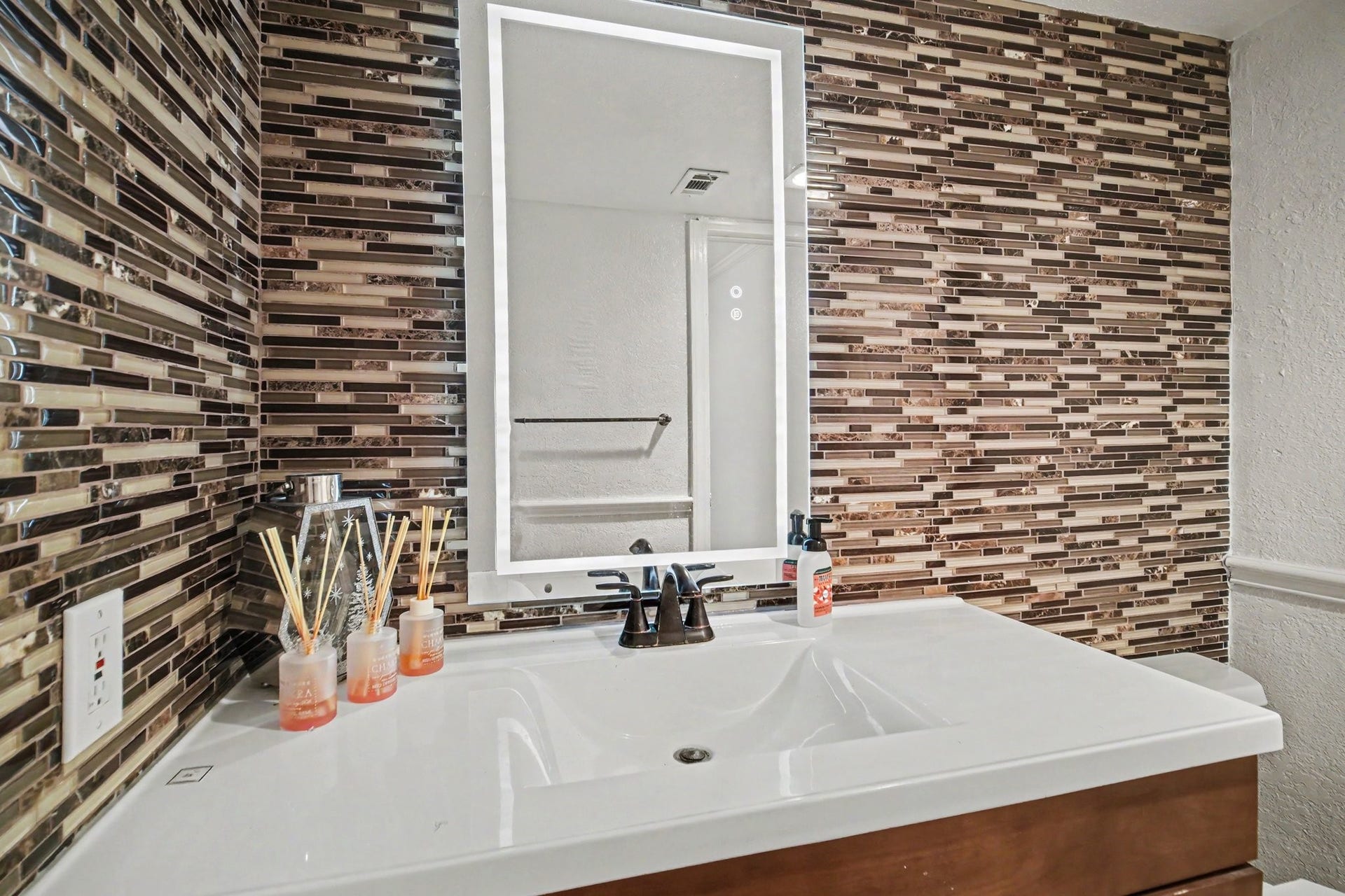 Chic half bath with a sleek vanity and a stunning mosaic tile wall, offering a perfect blend of style and functionality.