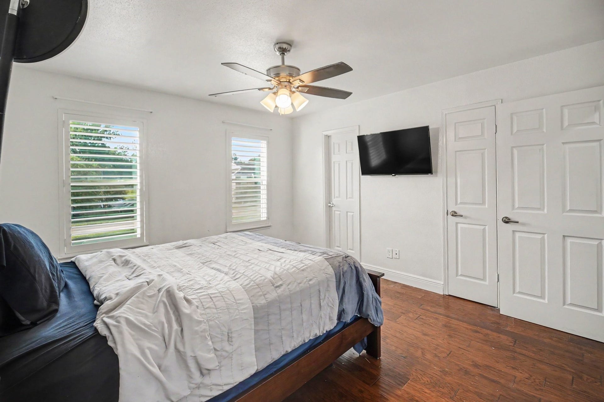 Bright and inviting, the second bedroom features rich hardwood floors, ample natural light from multiple windows, and a sleek modern ceiling fan for ultimate comfort.