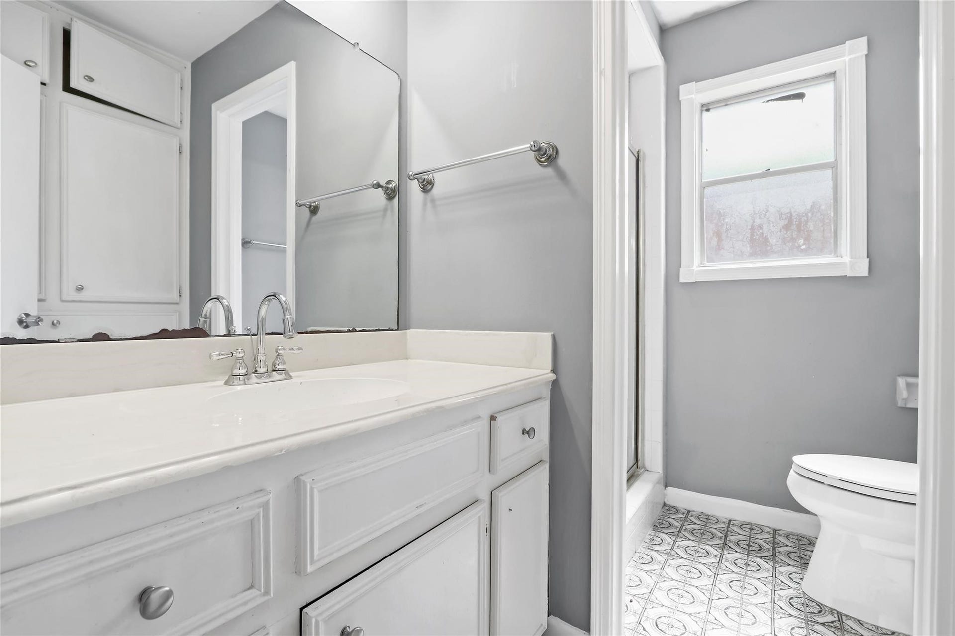 Primary ensuite bathroom featuring an extended vanity with ample cabinet space, a walk-in shower, and natural light.