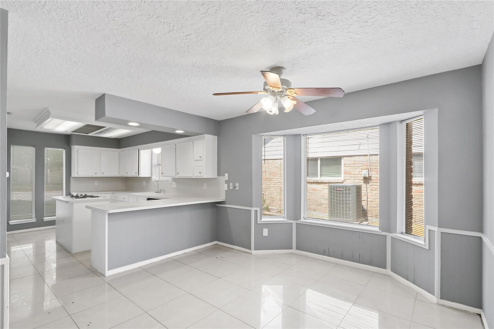 Another view of the spacious breakfast area, featuring bay windows and an open layout connecting to the kitchen with breakfast bar seating.