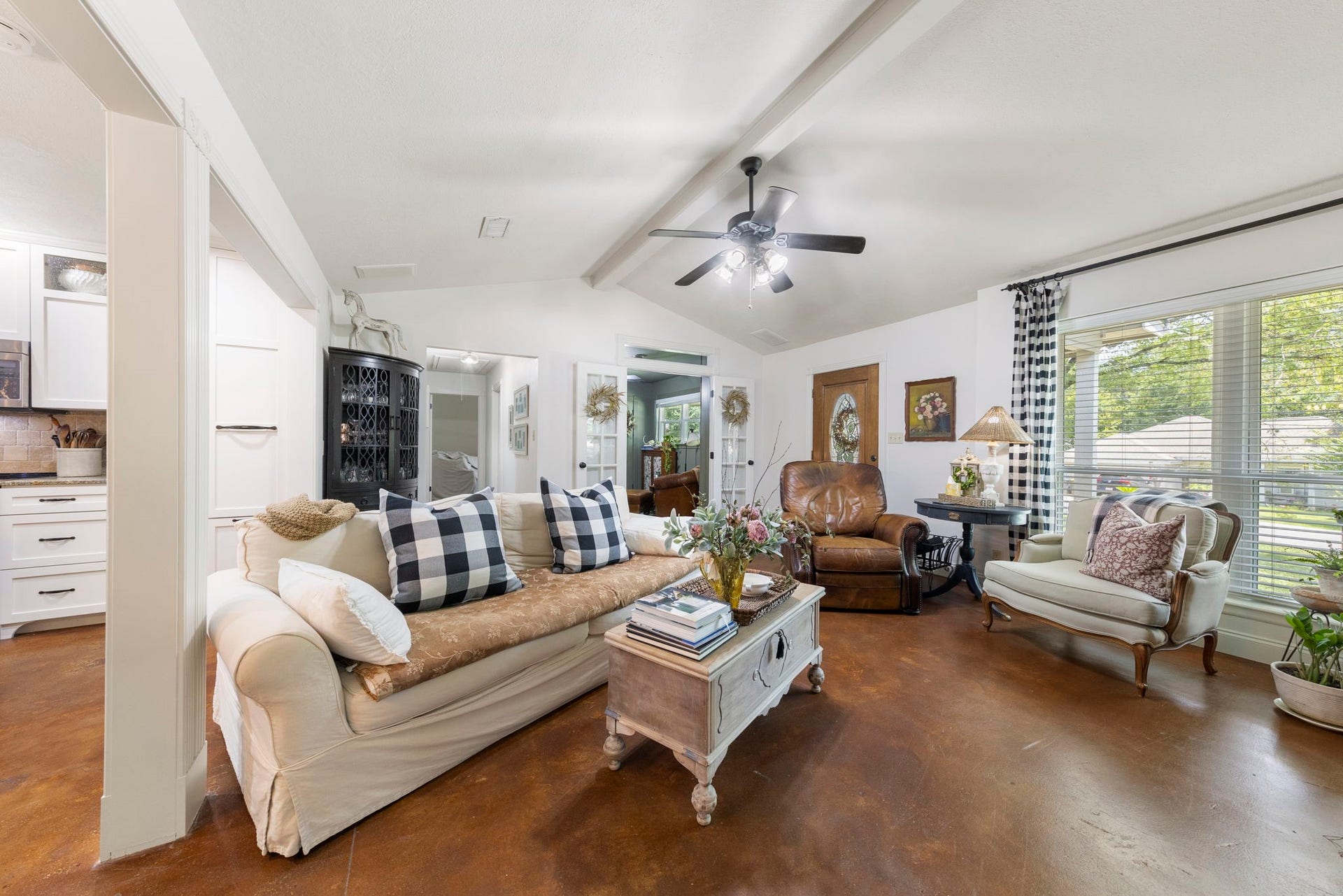 Bright, inviting living room with vaulted ceilings, charming architectural details, warm flooring, and abundant natural light.