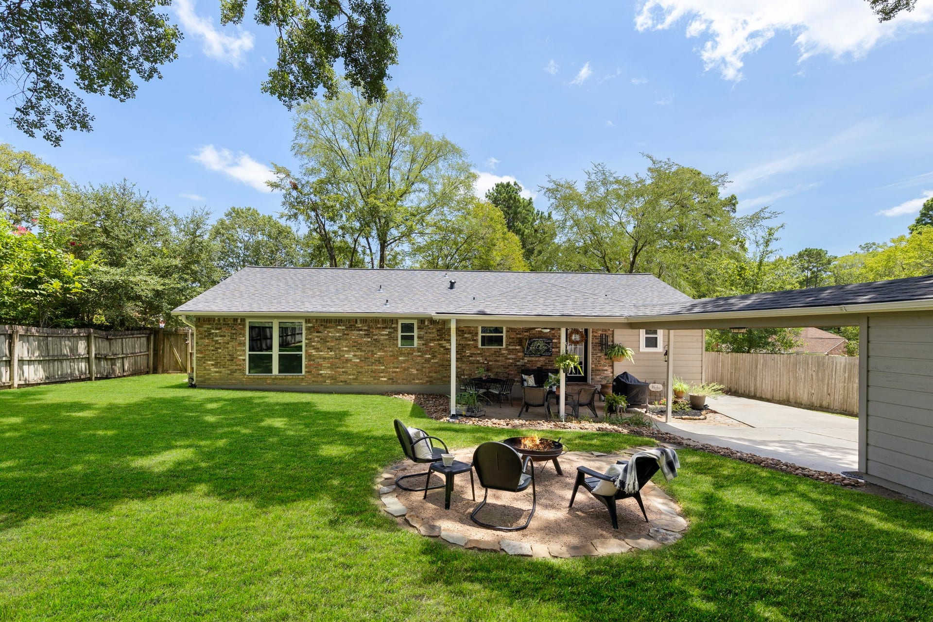 Enjoy a spacious backyard with mature trees, a fire pit, covered patio, and detached garage connected by a breezeway.