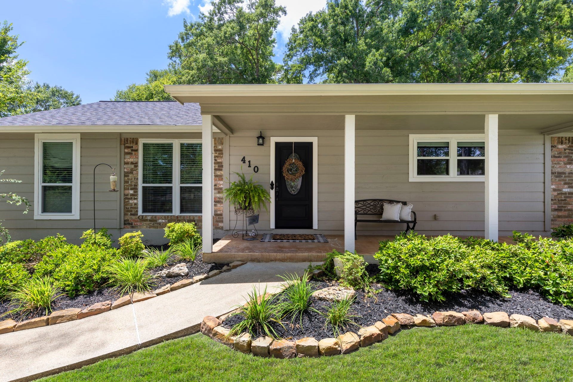 Charming front elevation with fresh landscaping, a welcoming covered front porch, and timeless curb appeal creates a warm first impression in this beautifully maintained home.