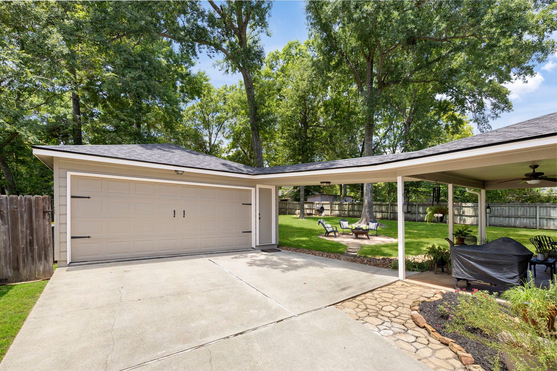 The detached two-car garage is connected by a covered breezeway, offering convenient sheltered access to the home and backyard. The expansive, fully fenced backyard features mature shade trees, a fire pit gathering area, and plenty of space for entertaining, recreation, or future outdoor additions.