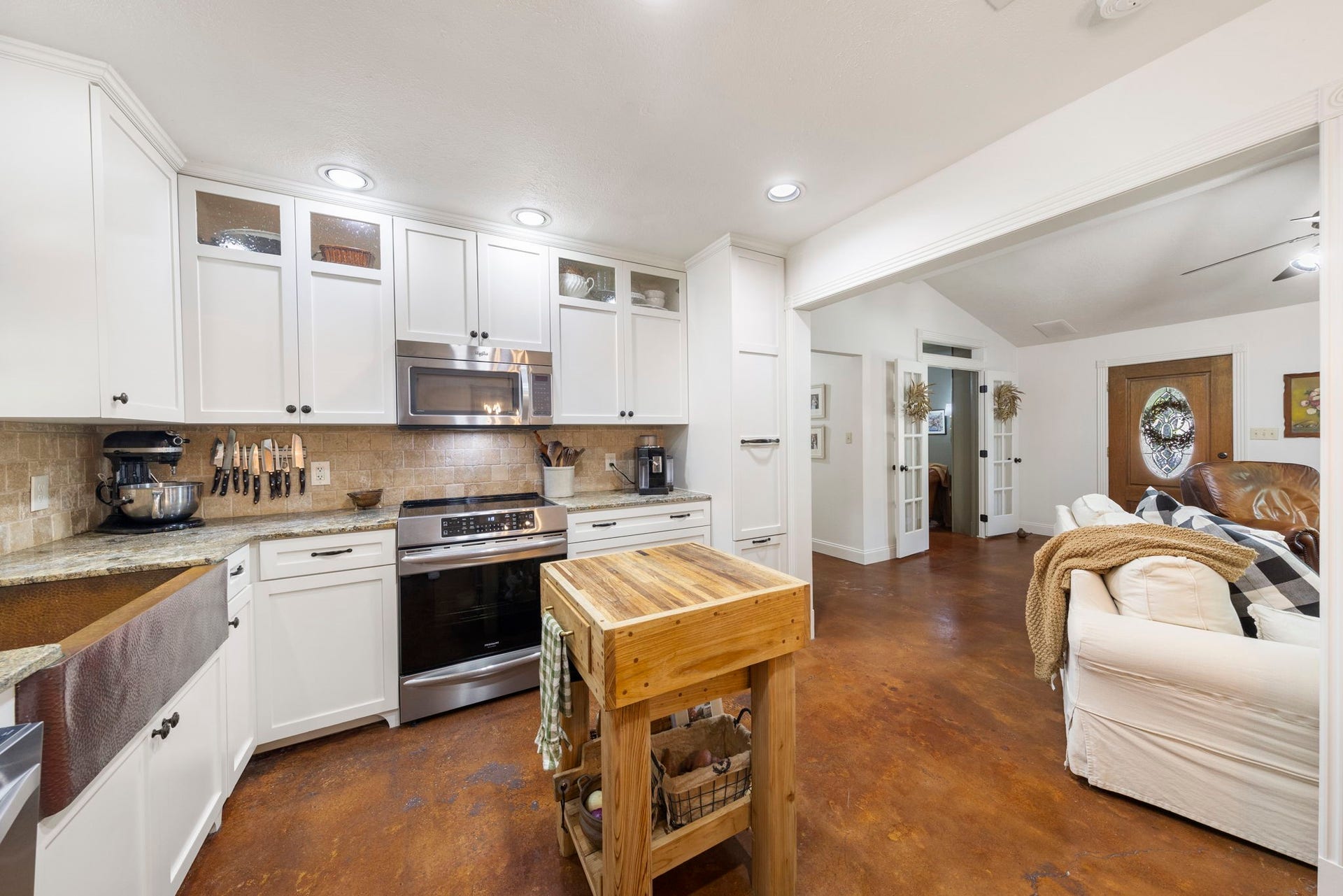 The updated kitchen blends timeless style with everyday functionality, featuring white cabinetry, stainless steel appliances, generous prep space, abundant storage, and an open layout that flows seamlessly into the living and dining areas.