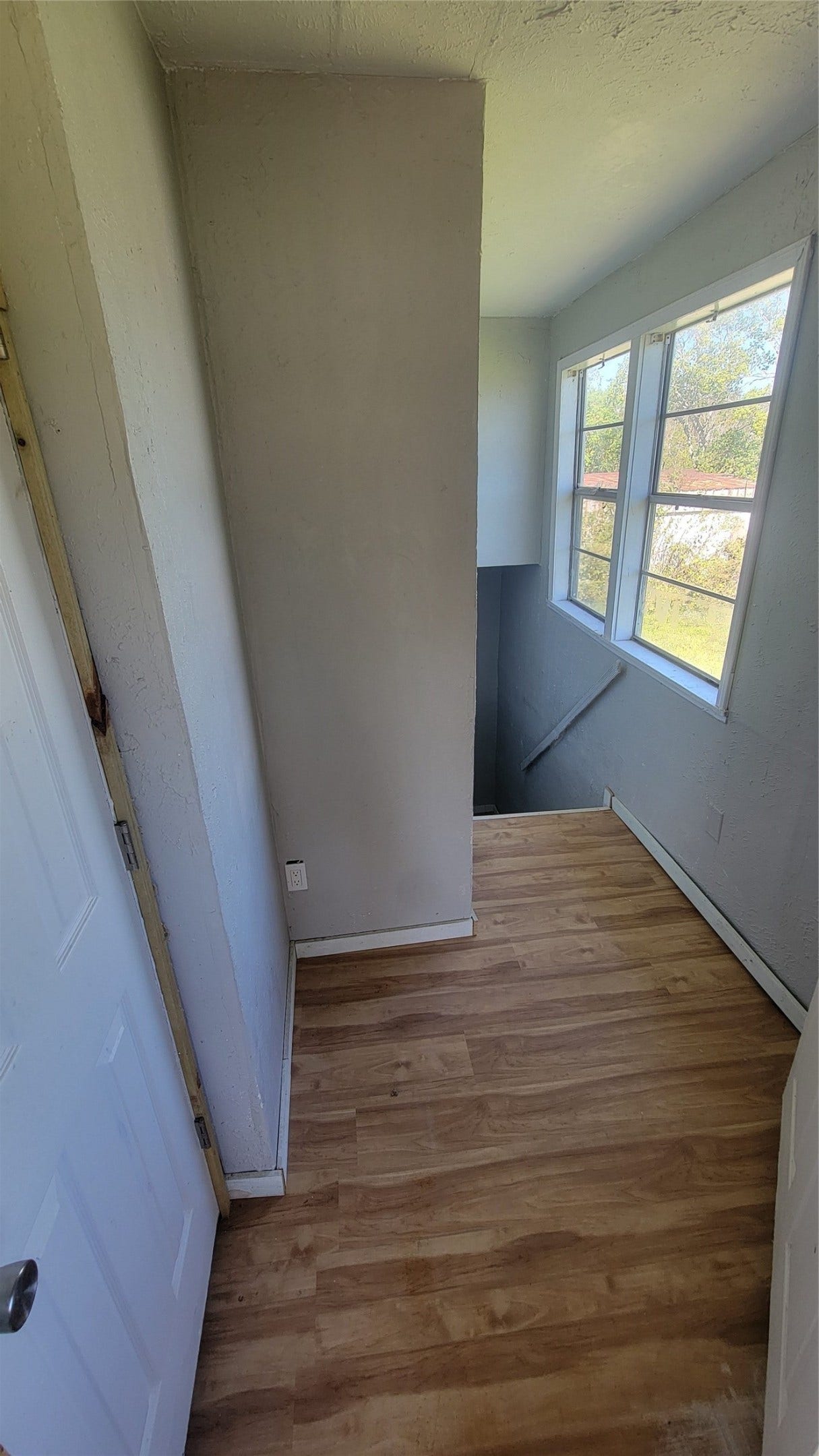 12018 Sandpiper Road, Angleton, TX 77515 This photo shows a small landing area with wooden flooring, leading to a staircase. It features a window with natural light and a simple, neutral color scheme.