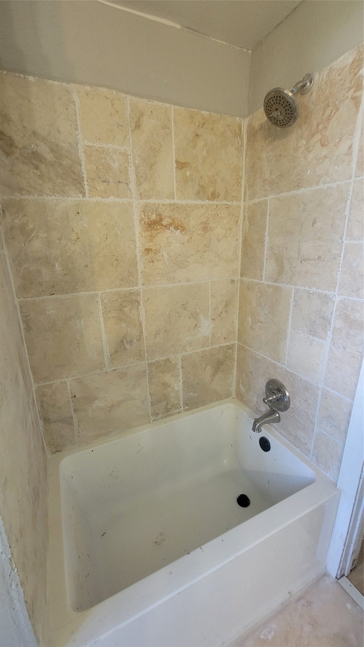 12018 Sandpiper Road, Angleton, TX 77515 This photo shows a simple bathroom with a white bathtub and beige tiled walls, featuring a showerhead and faucet.