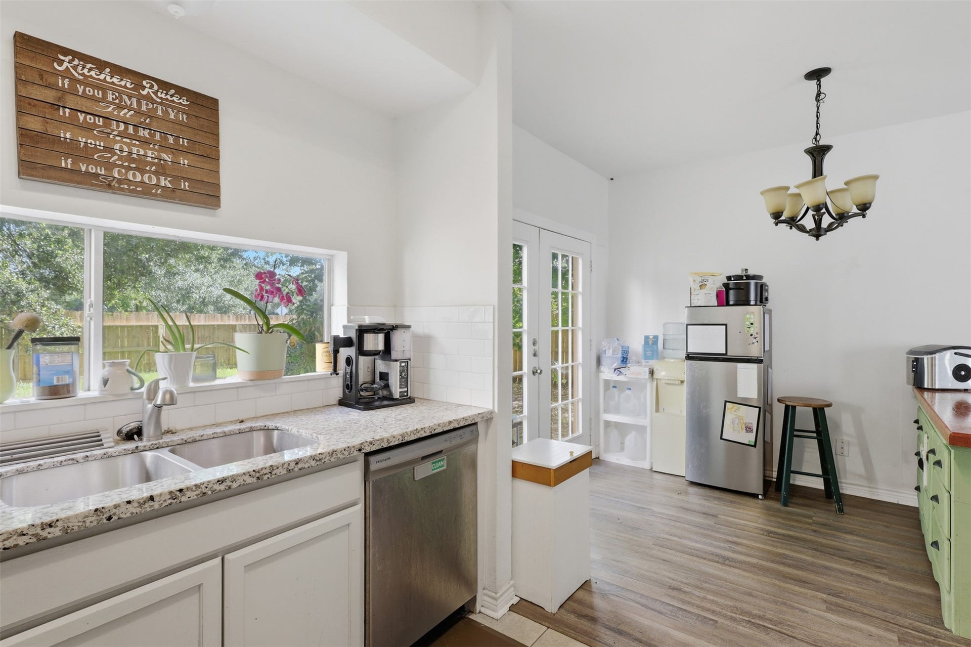 Under-mount sink positioned beneath a picturesque window, complete with full-sized dishwasher space and quick outdoor access for summer barbecues.