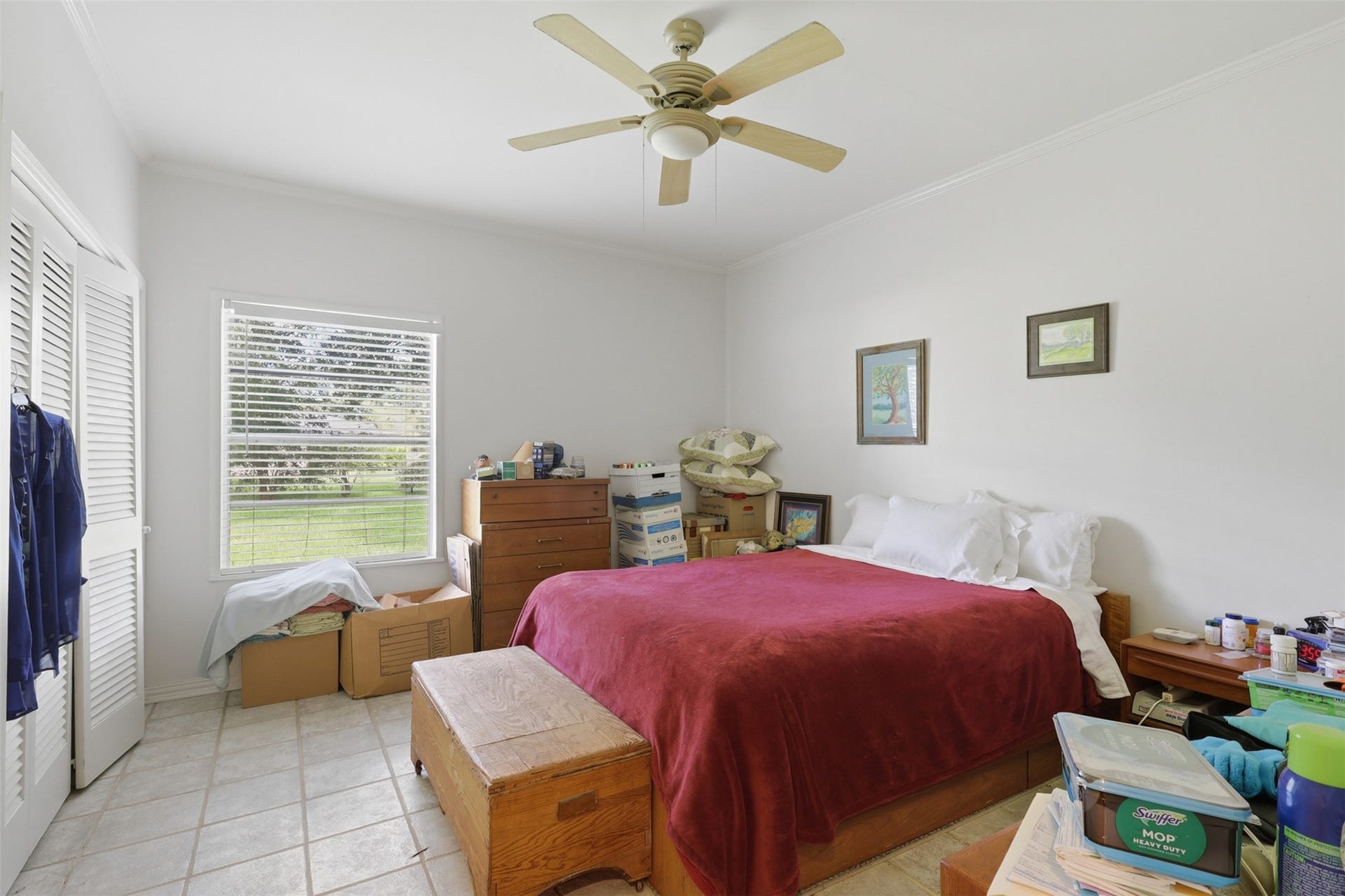 Low-maintenance tile flooring and a refreshing ceiling fan complement a bright bedroom layout, complete with generous closet space and peaceful views.