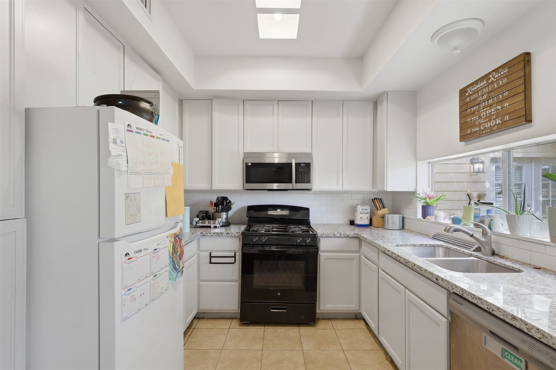 Space: Sleek white cabinetry paired with stone-look countertops, stainless steel appliances, and a garden window perfect for fresh herbs.
