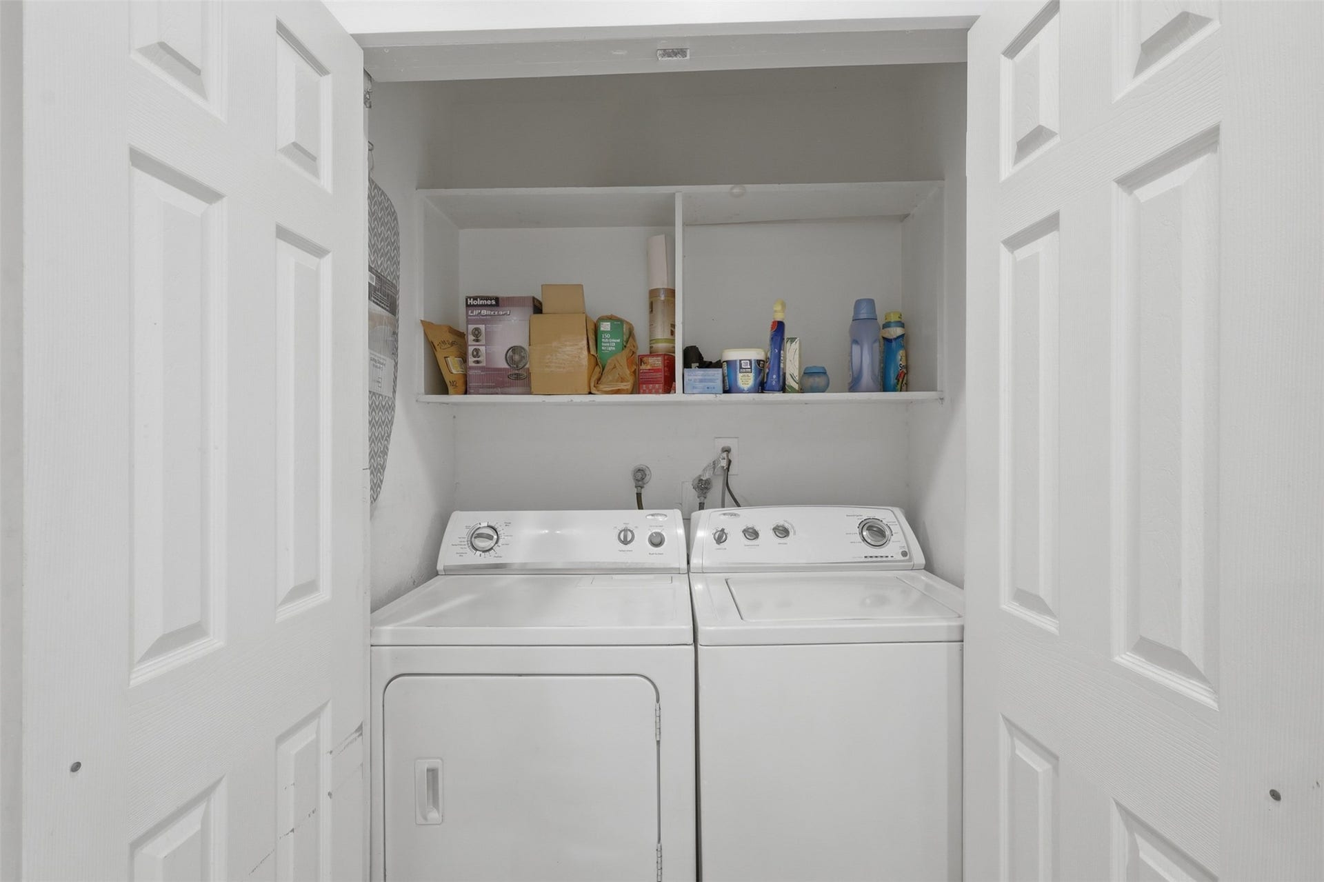 Cleverly organized double-door utility zone featuring built-in overhead storage shelves to keep essentials neatly tucked away.