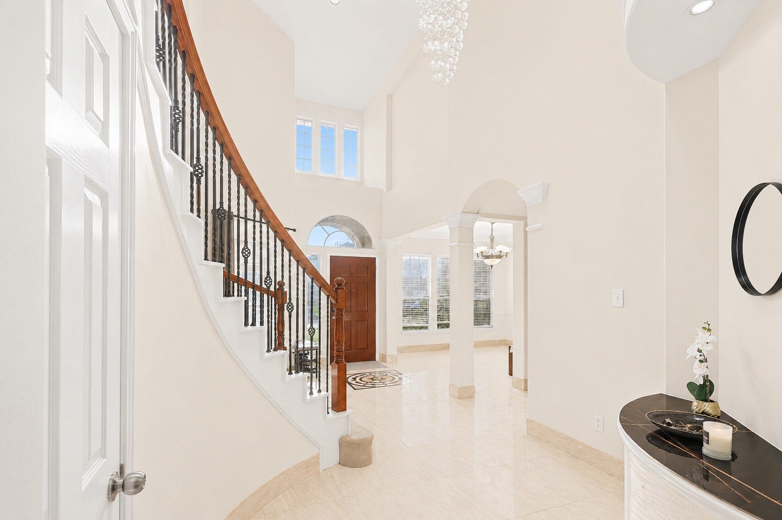 2614 Sunset Lake Drive, Sugar Land, TX 77478 Bright and elegant foyer with a grand curved staircase, high ceilings, and large windows. The space features polished floors, a stylish chandelier, and an inviting entrance that leads to an open living area.
