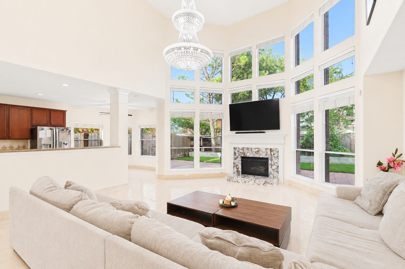 2614 Sunset Lake Drive, Sugar Land, TX 77478 This spacious living room features high ceilings, abundant natural light from large windows, and a cozy fireplace. The open layout flows into the kitchen, offering a modern and welcoming atmosphere perfect for entertaining.