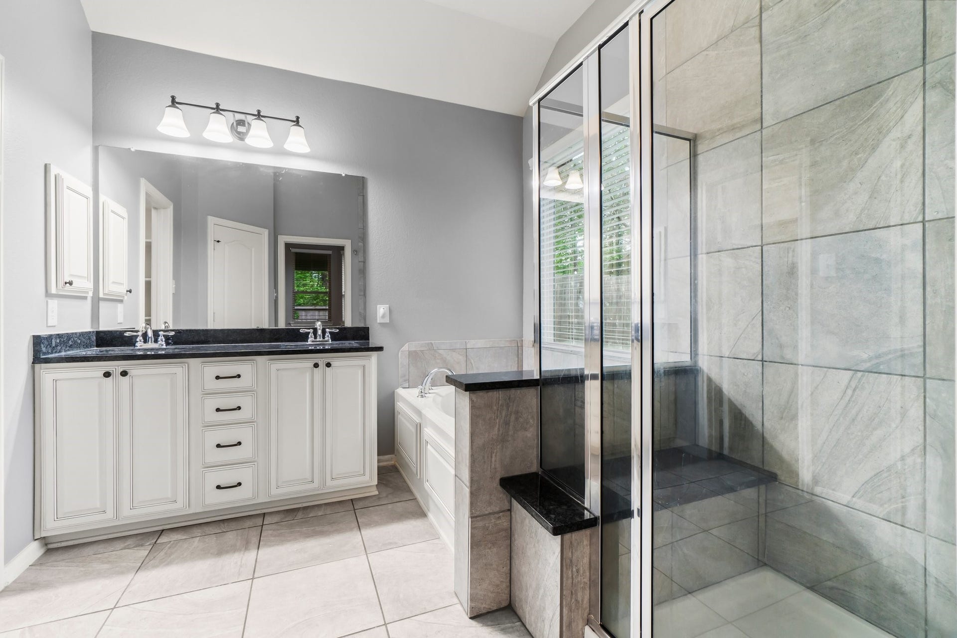 The primary bathroom boasts a separate shower, a corner bathtub, and double sinks, all enhanced by abundant natural light.