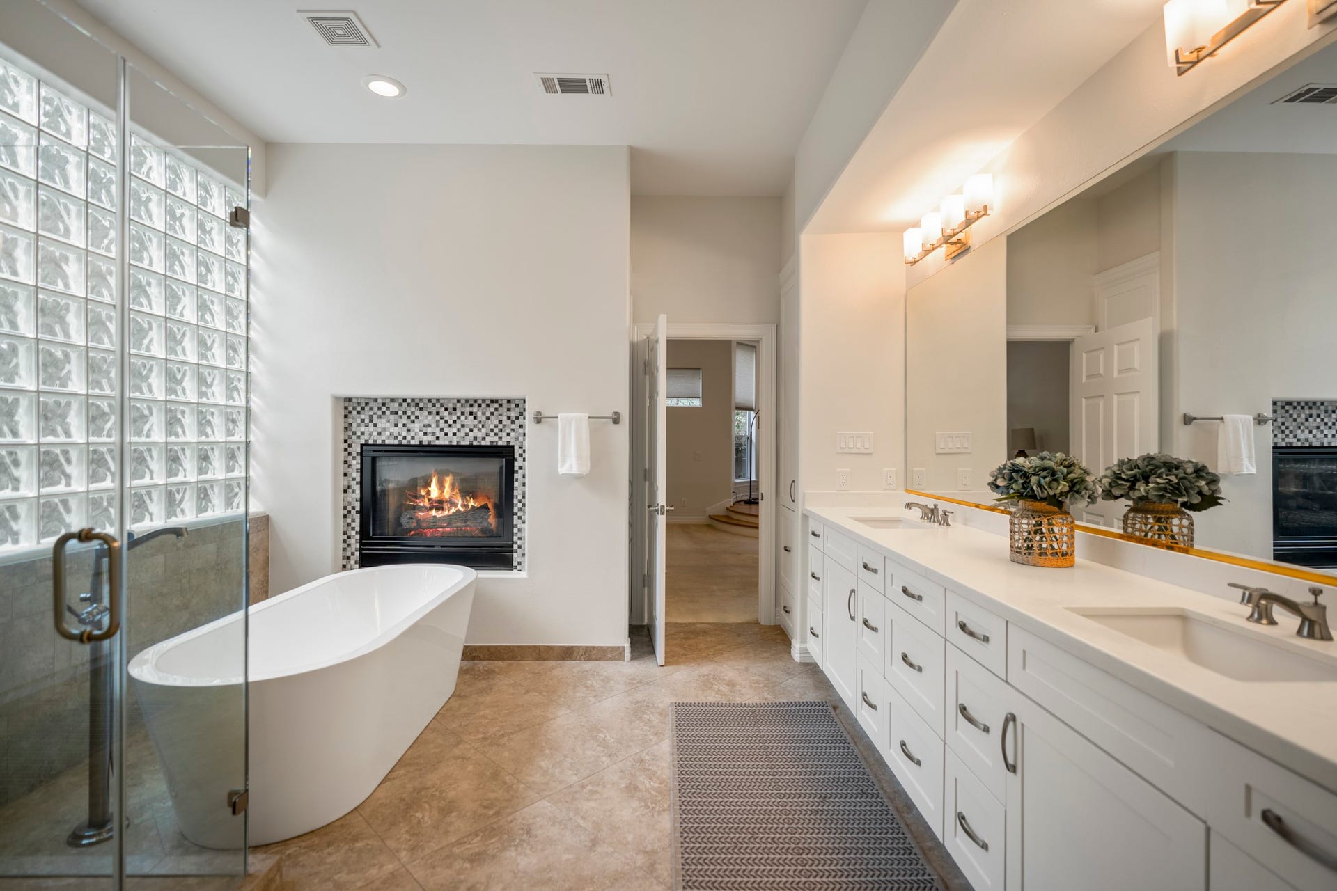 863 Plainwood Drive, Houston, TX 77079 The renovated primary bathroom features dual quartz-topped vanities, a freestanding tub and open shower.