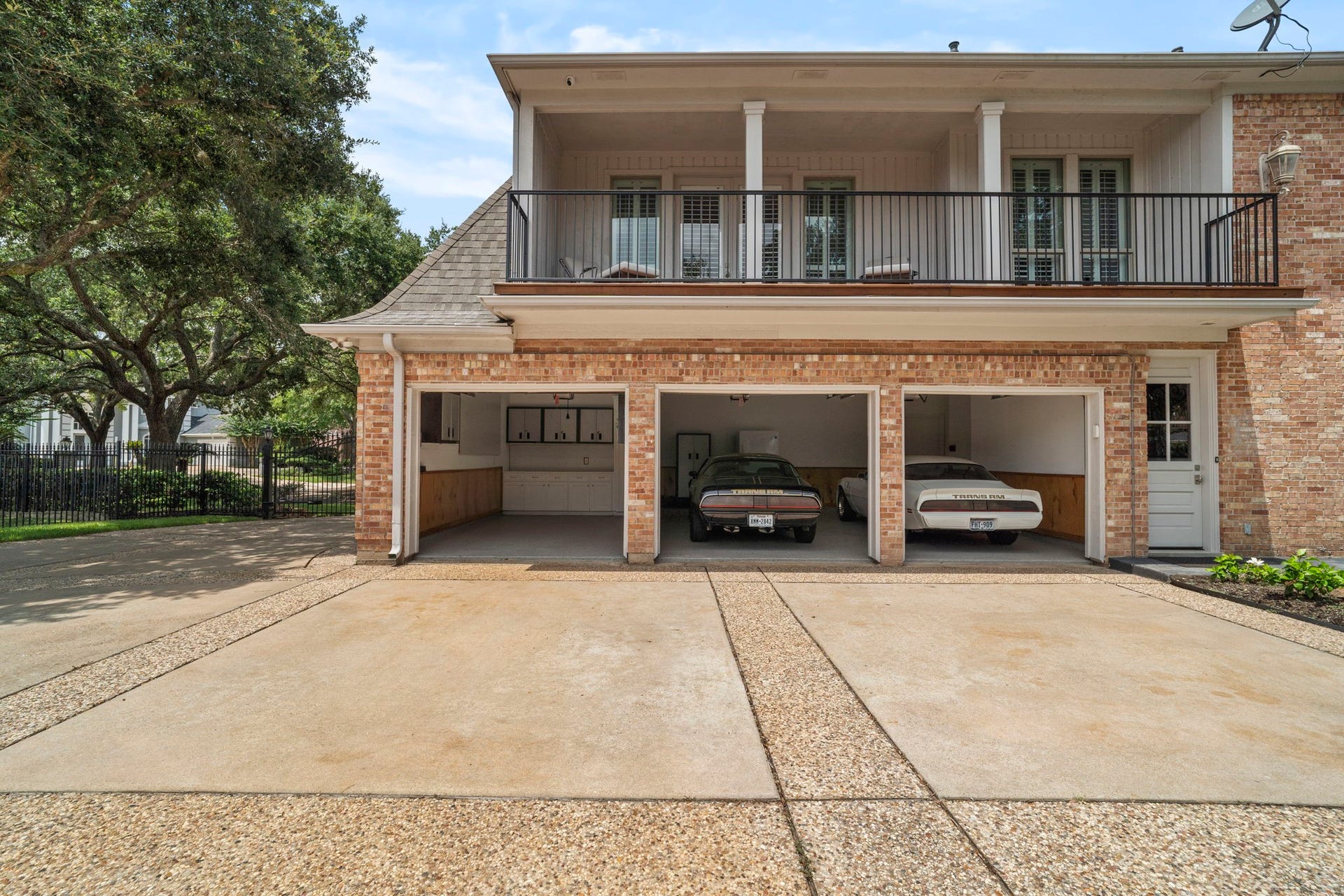 A gated motor court leads to a three-car, side-by-side garage complete with custom workshop built-ins.