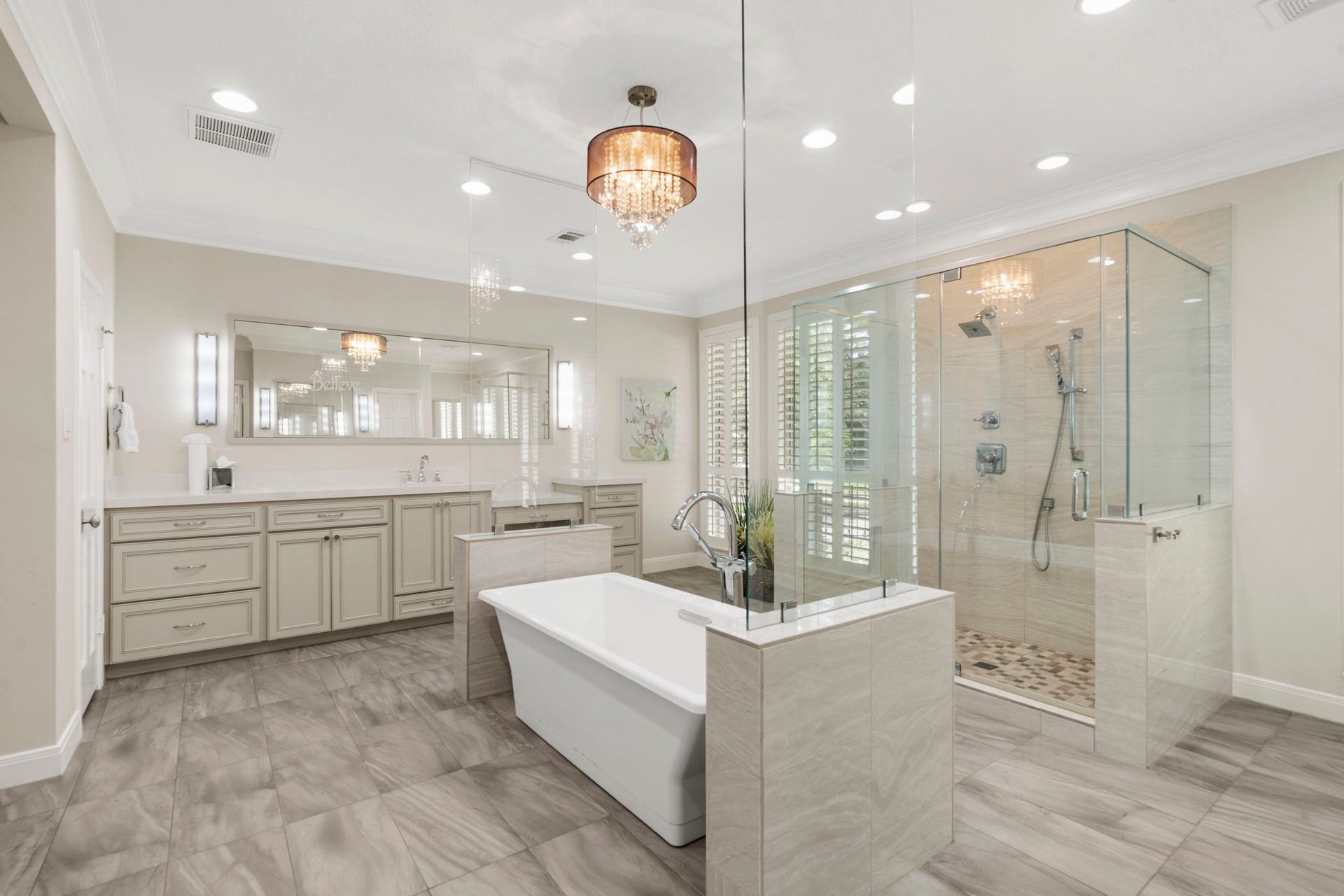 A luxurious owner's bath showcases a freestanding soaking tub, frameless glass shower, dual vanities, and separate private water closets.