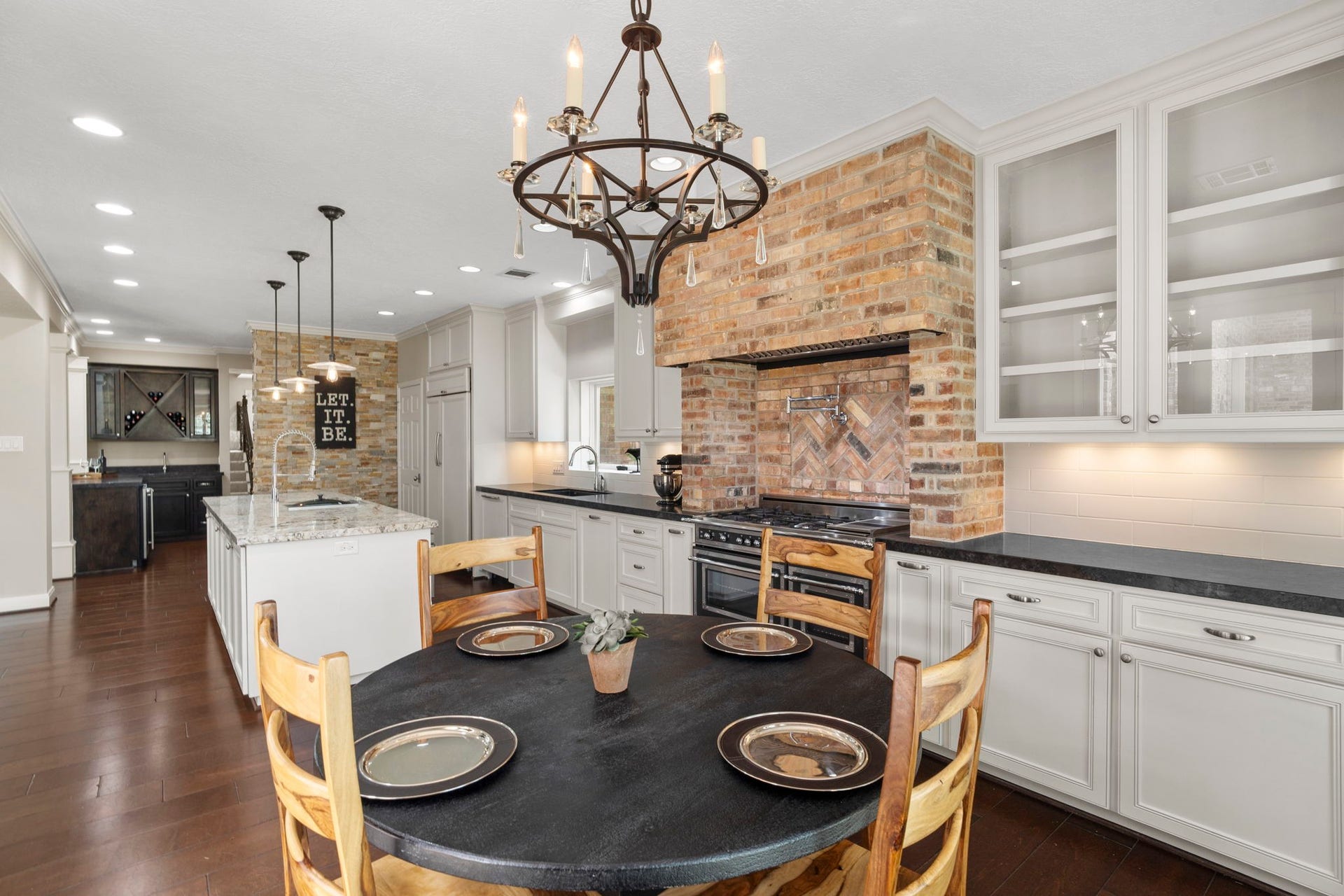 Every detail has been thoughtfully considered, from custom glass-front built-in cabinetry and generous counter space to pull-out spice and baking sheet storage flanking the range.