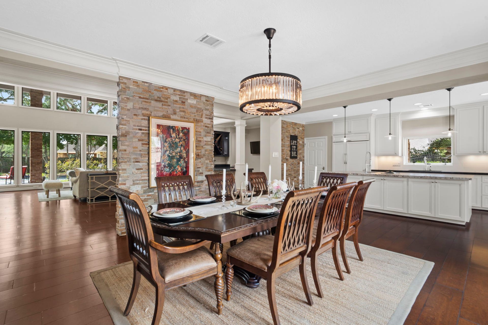 Defined by a partial stone accent wall, the dining room features a dazzling Restoration Hardware crystal drum chandelier.
