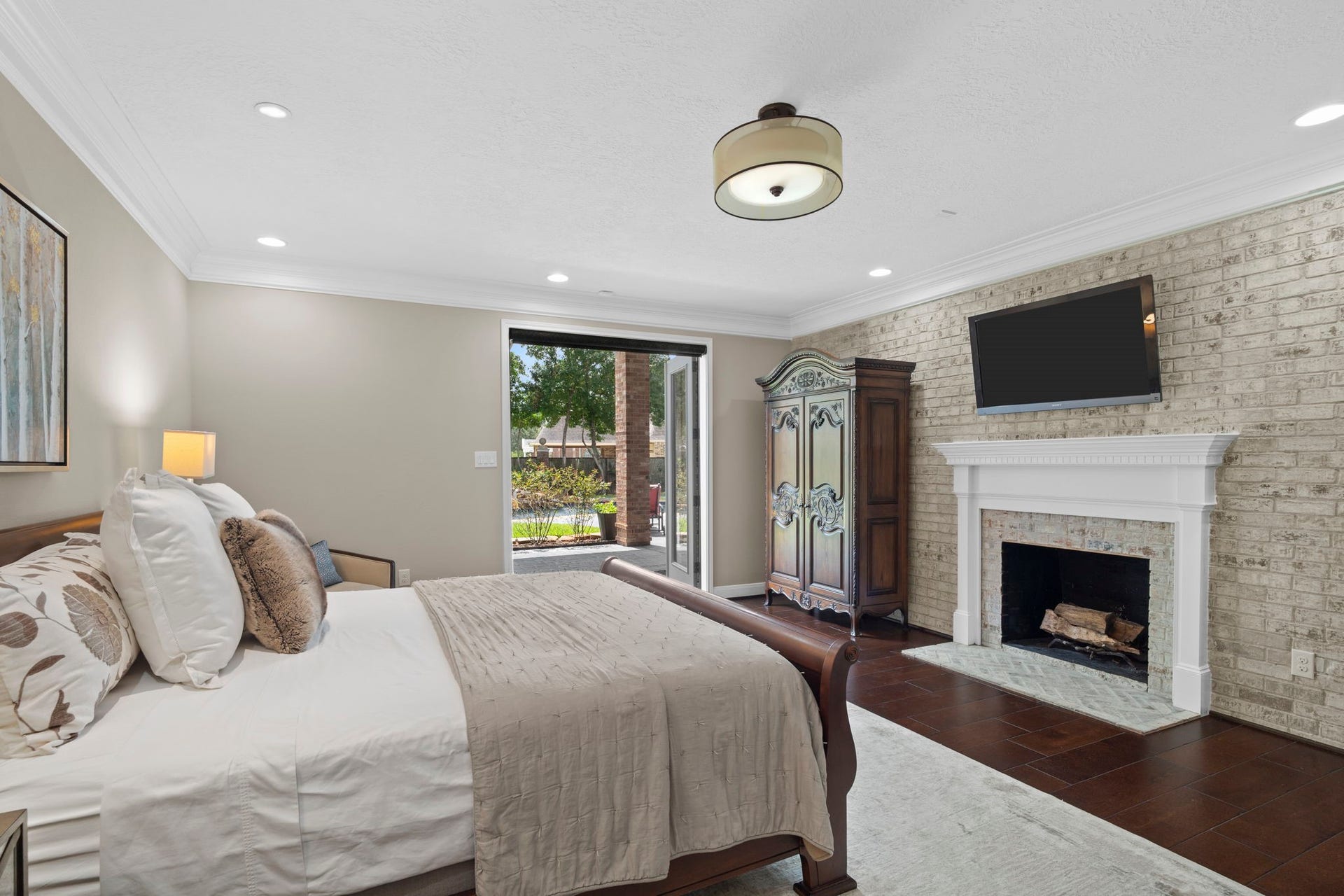 The owner's suite showcases a German schmear brick accent wall and classic fireplace, adding warmth, texture, and timeless character.