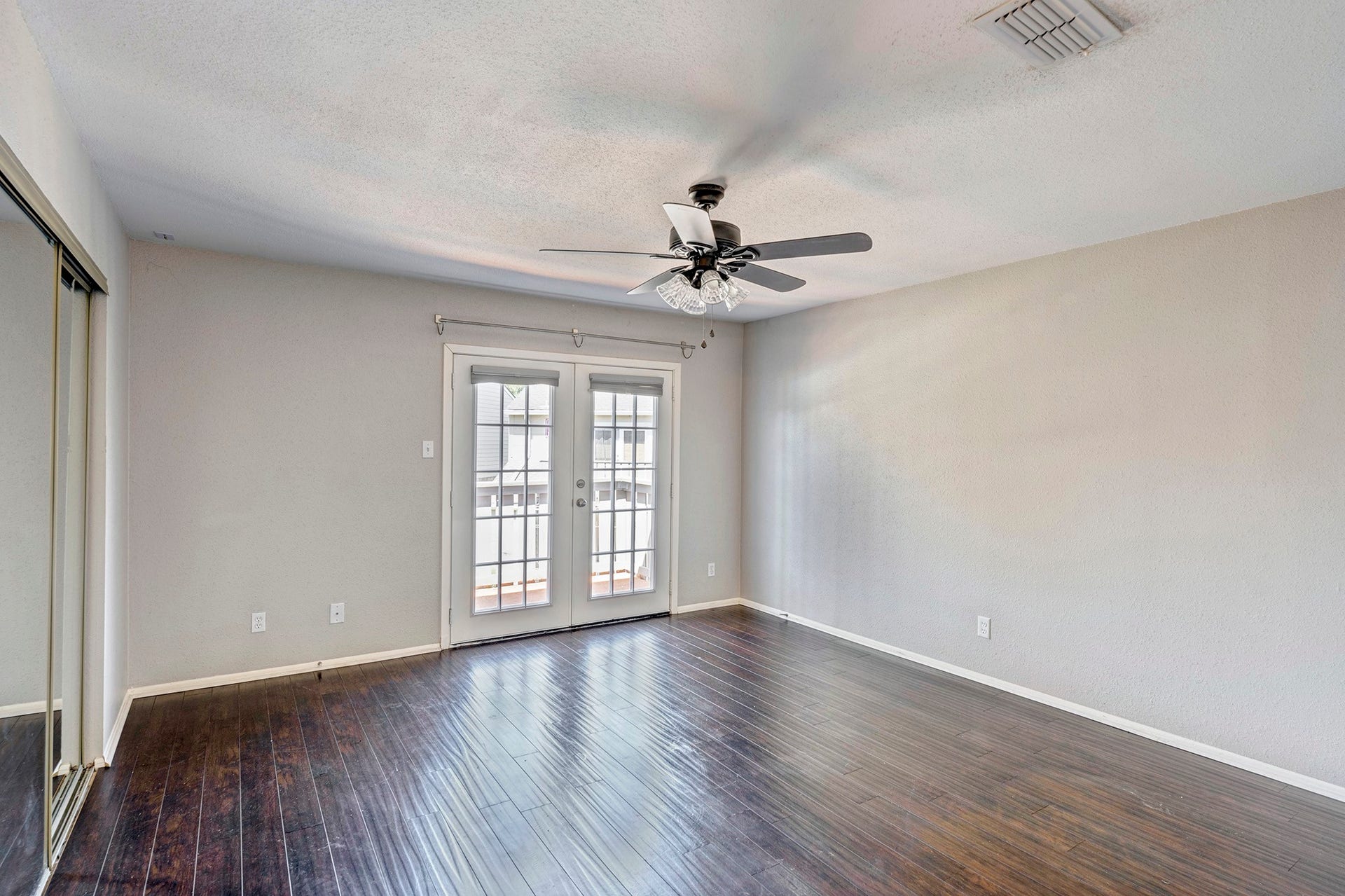 5005 Georgi Lane, #165, Houston, TX 77092 Back bedroom with french doors to the balcony, mirrored sliding closet doors and ceiling fan.