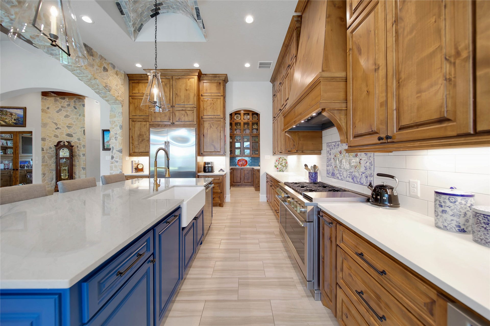24718 Shadow Pond Drive, Spring, TX 77389 Stunning kitchen featuring a blend of rustic charm and modern elegance with rich wood cabinetry, sleek stainless steel appliances, and a spacious island with striking blue accents.