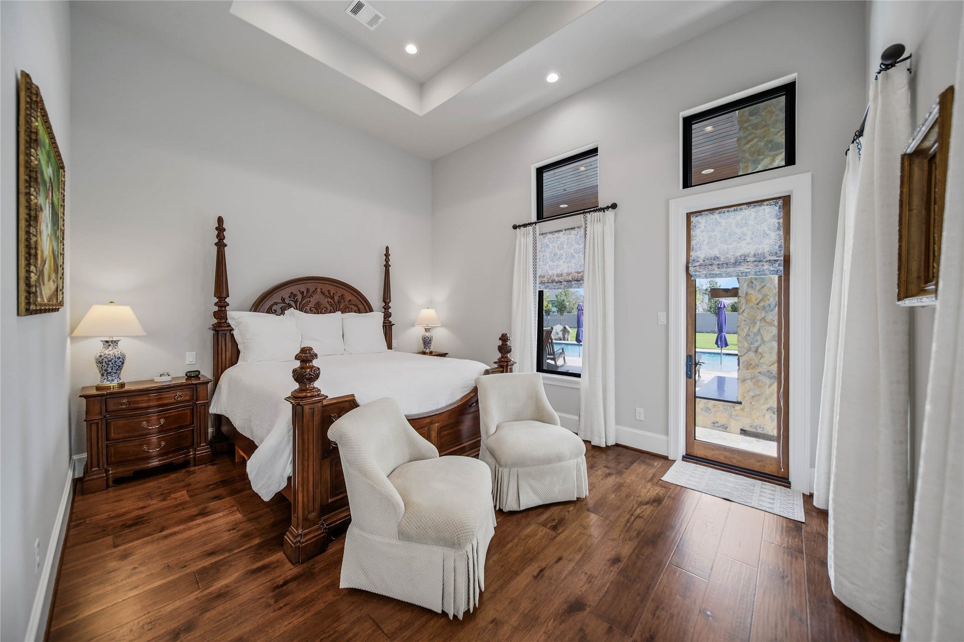 24718 Shadow Pond Drive, Spring, TX 77389 Elegant bedroom with rich hardwood flooring, a stately four-poster bed, and abundant natural light from large windows and a glass door leading to the patio.
