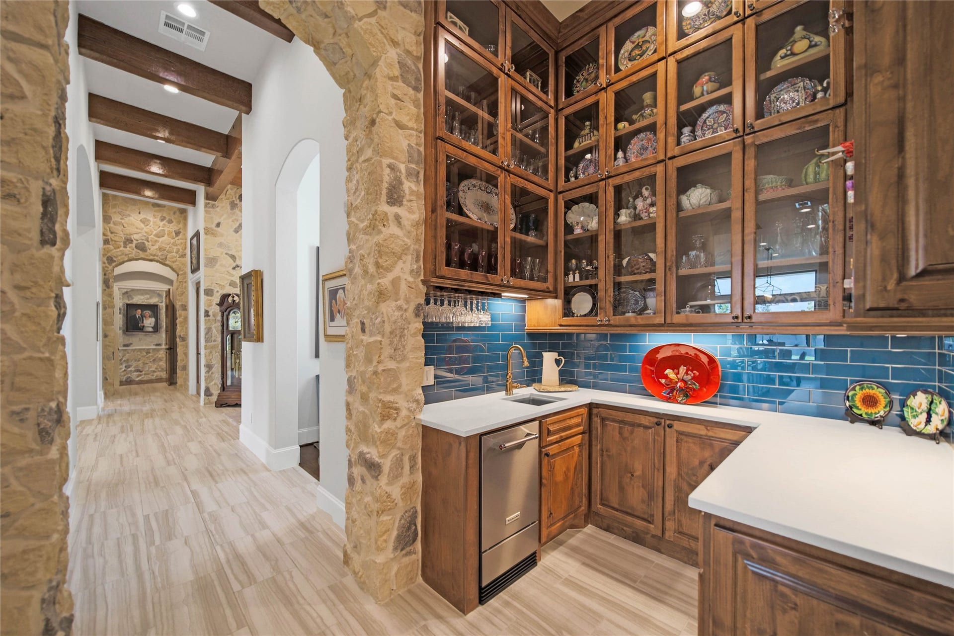 24718 Shadow Pond Drive, Spring, TX 77389 Charming kitchen area with rustic stone accents and elegant wooden cabinetry, featuring a striking blue tile backsplash and ample display space for fine china.