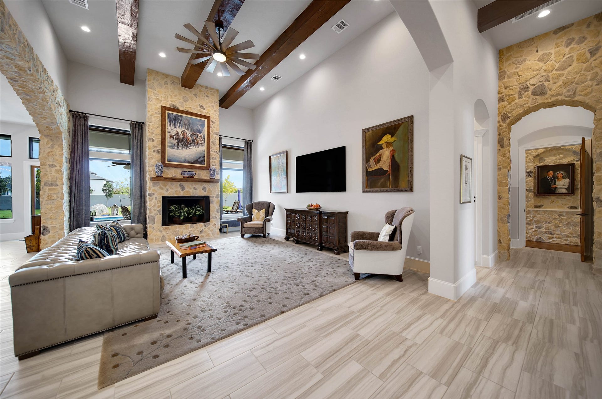 24718 Shadow Pond Drive, Spring, TX 77389 Elegant living room featuring a stunning stone fireplace, high ceilings with wooden beams, and abundant natural light from large windows, creating a warm and inviting atmosphere.