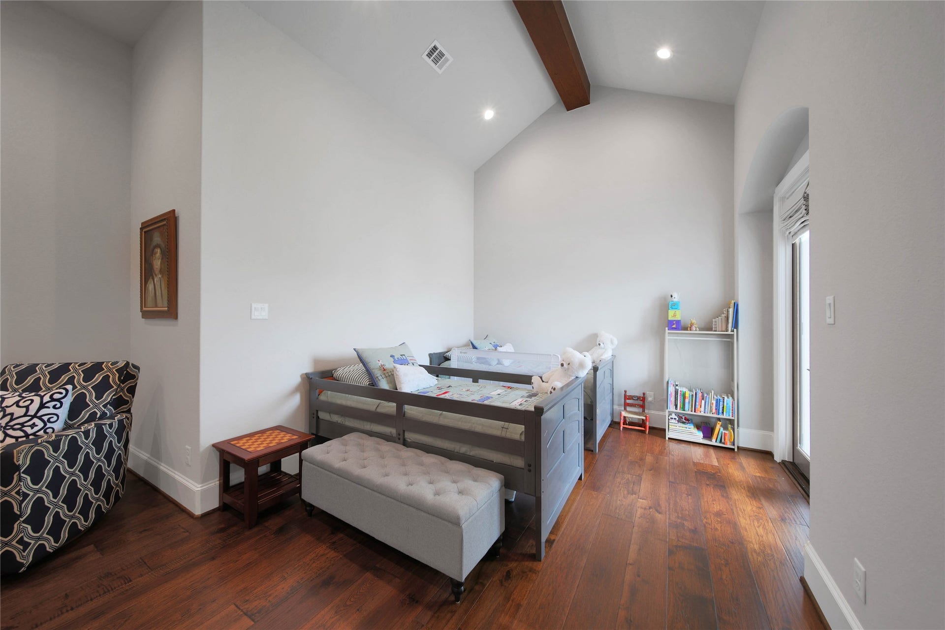 24718 Shadow Pond Drive, Spring, TX 77389 Charming bedroom with high ceilings and warm hardwood floors, featuring a cozy reading nook and ample natural light from a large window.