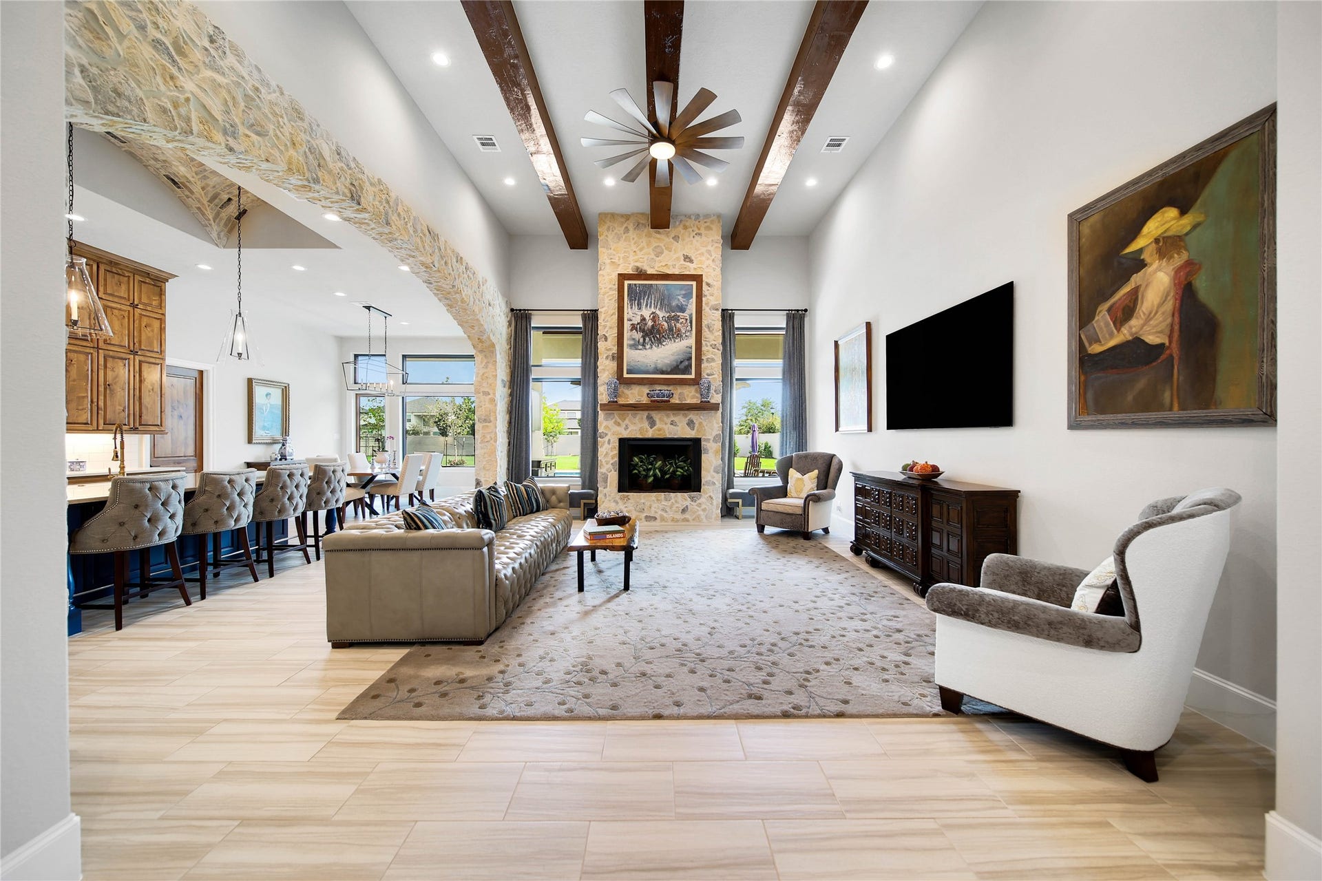 24718 Shadow Pond Drive, Spring, TX 77389 Stunning living space with high ceilings, exposed wooden beams, and a stone fireplace. The open layout flows seamlessly into a modern kitchen and dining area, perfect for entertaining. Large windows offer plenty of natural light and picturesque views.