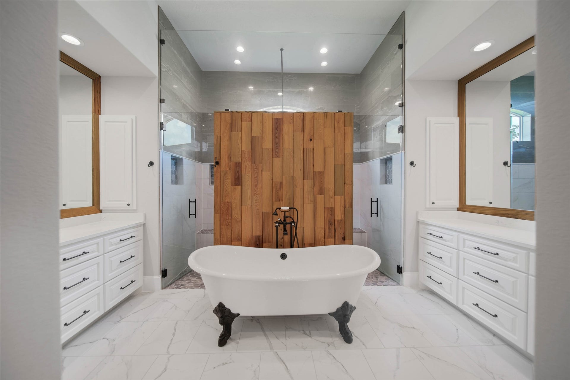 24718 Shadow Pond Drive, Spring, TX 77389 Luxurious bathroom featuring a freestanding clawfoot tub, elegant double vanities, and a spacious glass-enclosed shower, all accented by warm wood paneling and sleek white cabinetry.