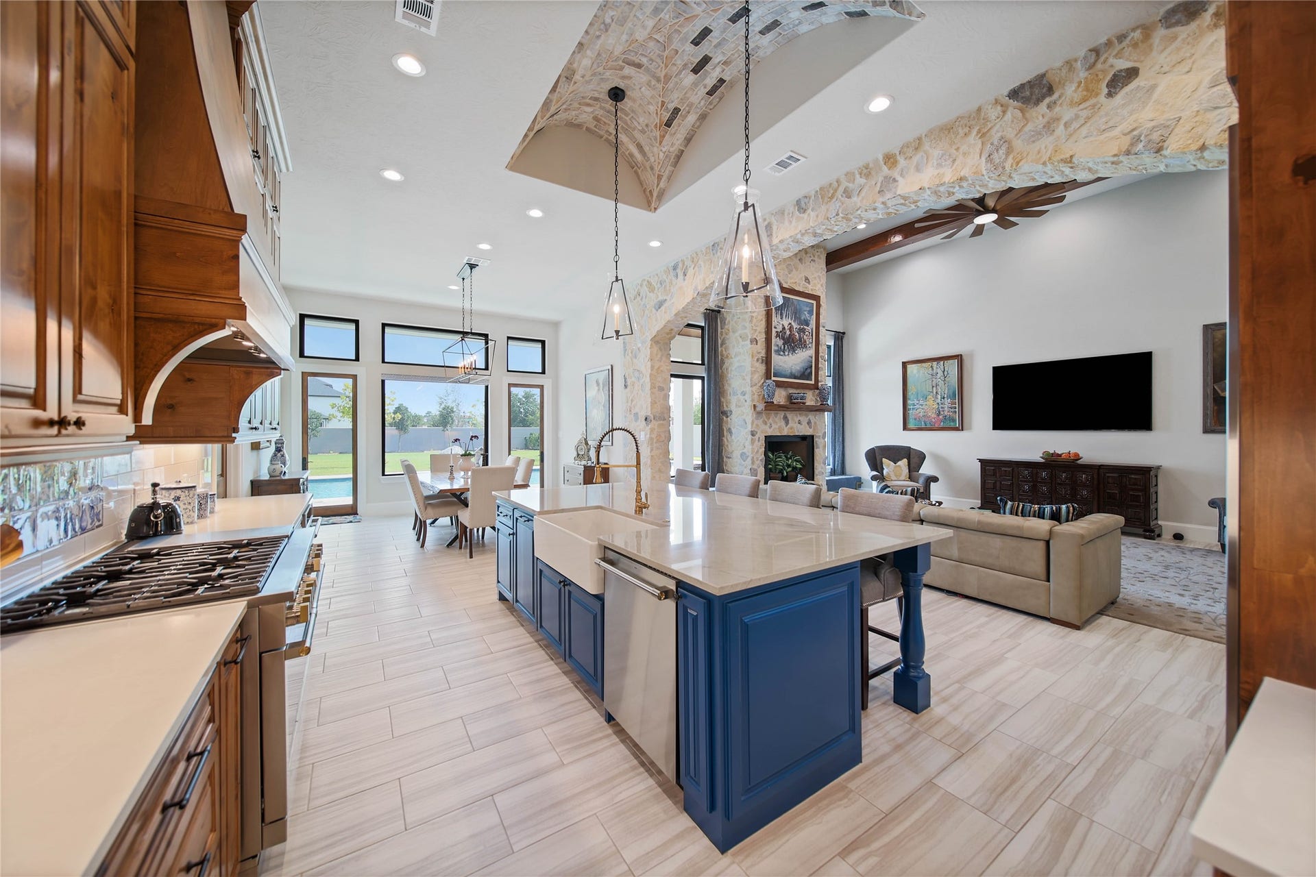 24718 Shadow Pond Drive, Spring, TX 77389 Experience open-concept living with a spacious kitchen featuring a bold blue island, elegant stone archways, and a cozy, inviting living area perfect for entertaining.
