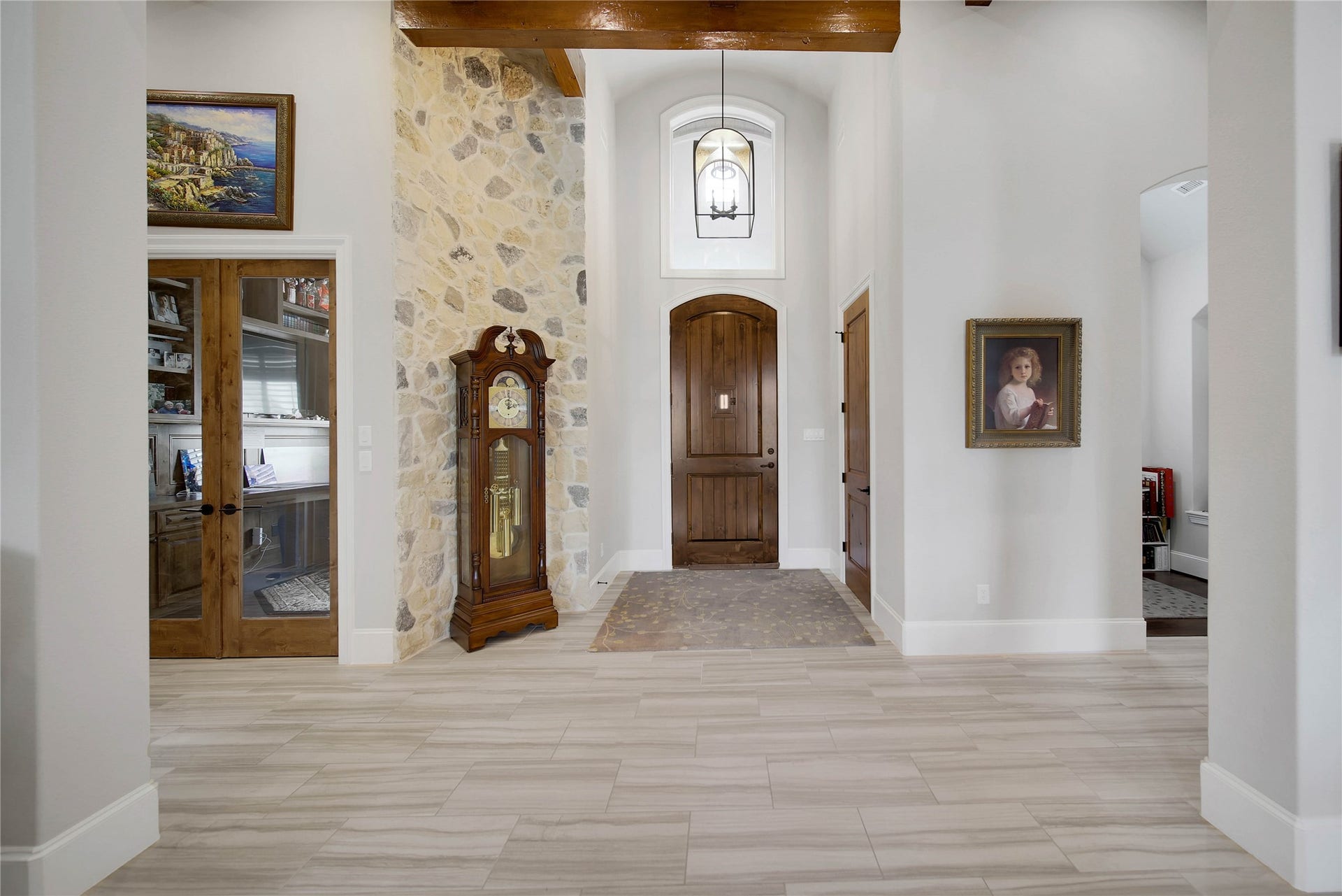 24718 Shadow Pond Drive, Spring, TX 77389 Elegant entryway featuring a grand wooden door, stone accent wall with a classic grandfather clock, and beautifully tiled flooring.