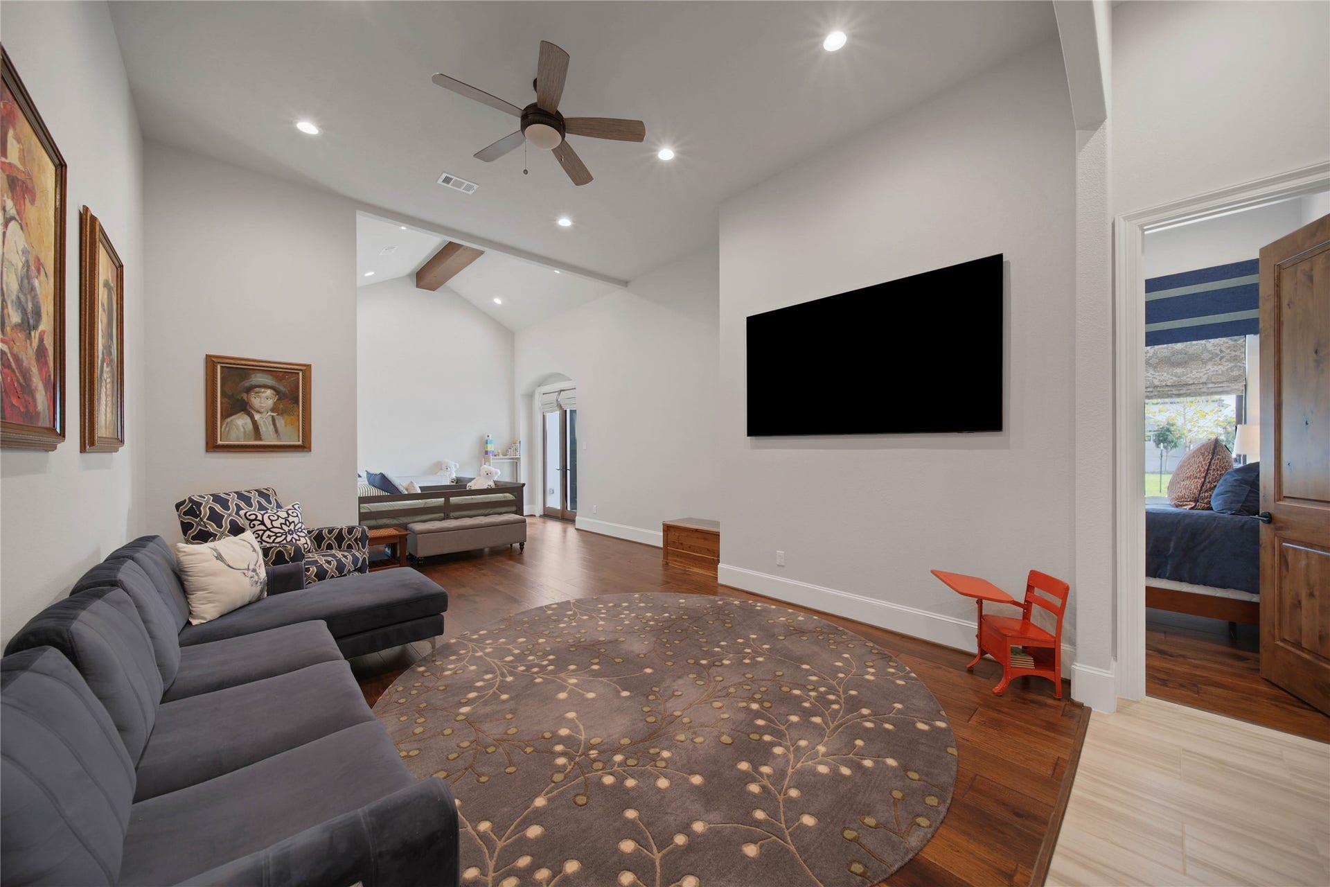24718 Shadow Pond Drive, Spring, TX 77389 Spacious living area with high ceilings, modern ceiling fan, and hardwood floors, featuring a comfortable seating arrangement and large wall-mounted TV.