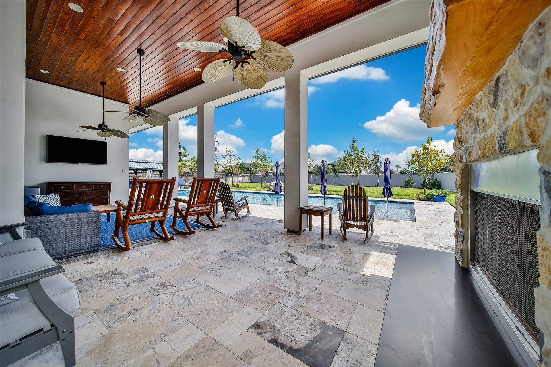 24718 Shadow Pond Drive, Spring, TX 77389 Experience outdoor luxury with a spacious patio featuring elegant tile flooring, ceiling fans, and a cozy fireplace. Overlooking a pristine pool, this area is perfect for relaxation and entertaining.