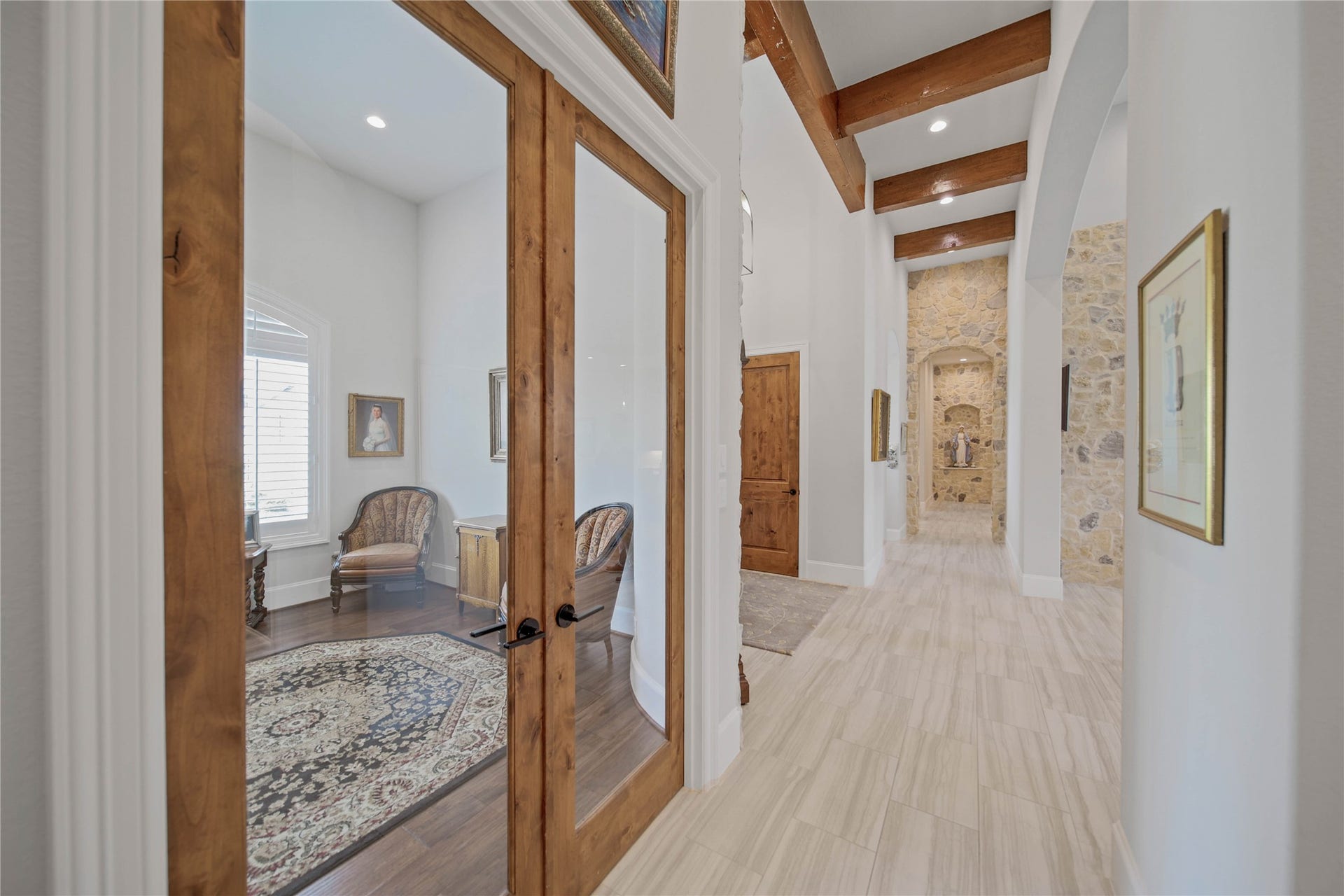 24718 Shadow Pond Drive, Spring, TX 77389 The elegant hallway features beautiful wooden beams and stone accents, leading to a cozy room with double glass doors, rich wood flooring, and abundant natural light.