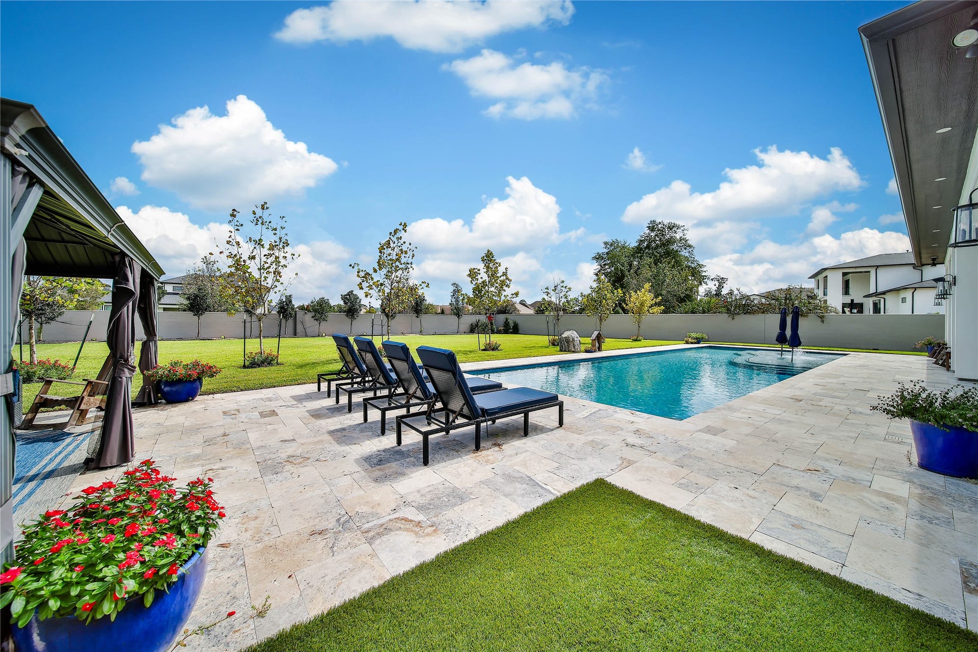 24718 Shadow Pond Drive, Spring, TX 77389 Luxurious backyard oasis featuring a sparkling pool surrounded by elegant stone decking, lush greenery, and ample lounge seating for relaxation.