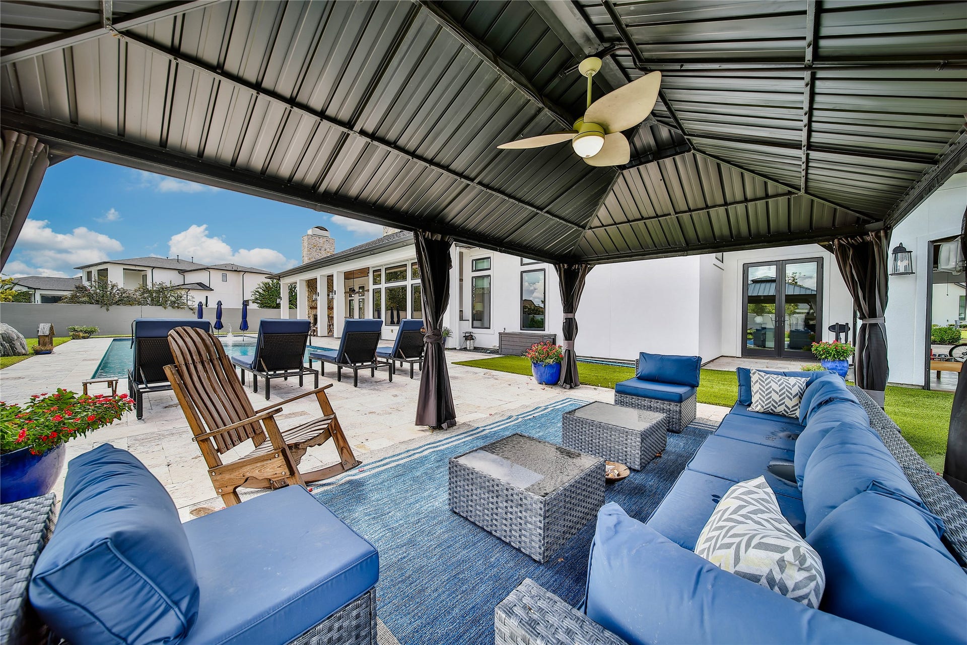 24718 Shadow Pond Drive, Spring, TX 77389 Luxurious outdoor living space featuring a spacious covered patio with comfortable seating, a ceiling fan, and views of the inviting pool area, perfect for relaxation and entertaining.