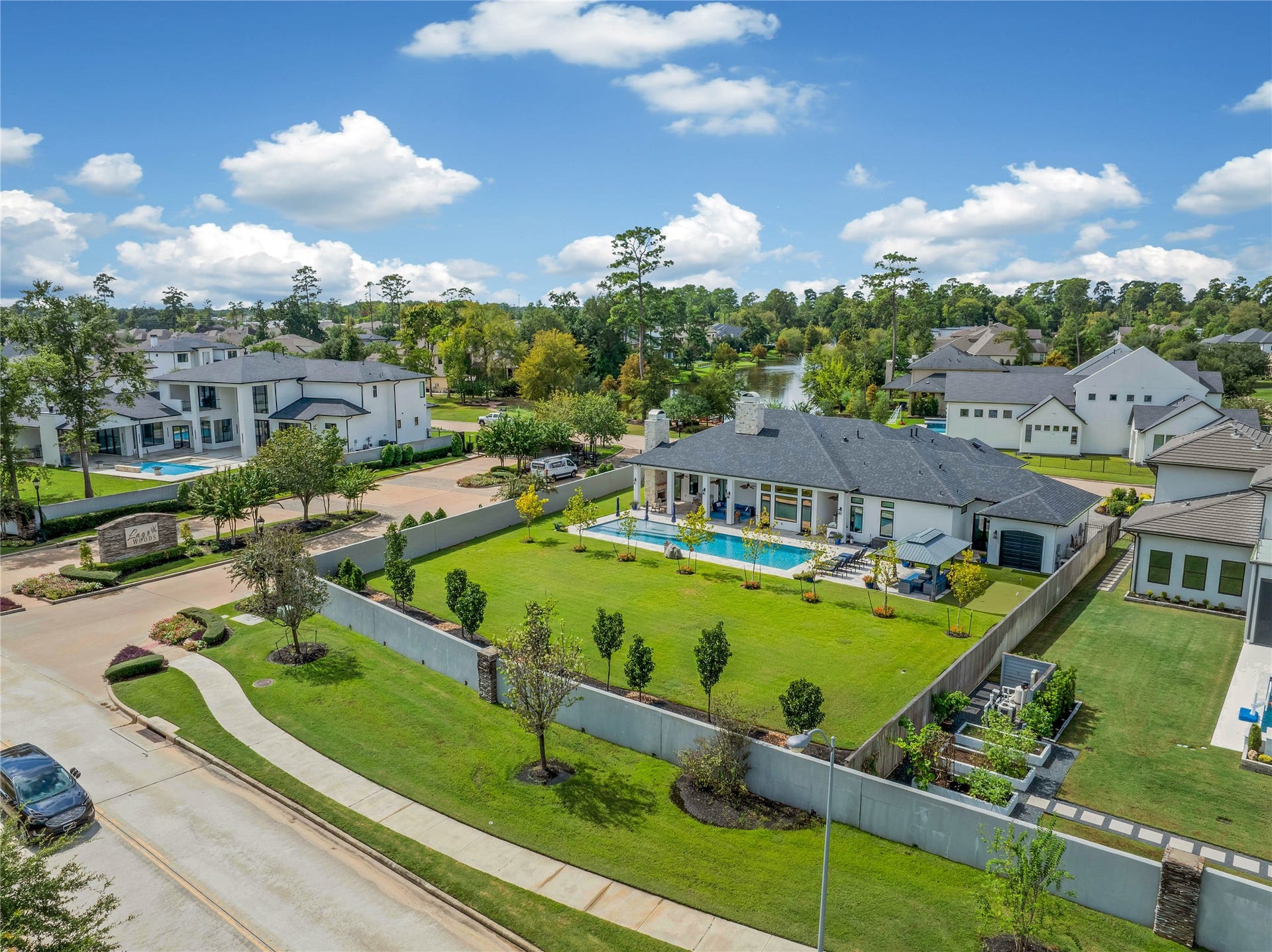 24718 Shadow Pond Drive, Spring, TX 77389 Sprawling modern estate with a luxurious pool, expansive lawn, and scenic water views, nestled in a tranquil, upscale neighborhood.