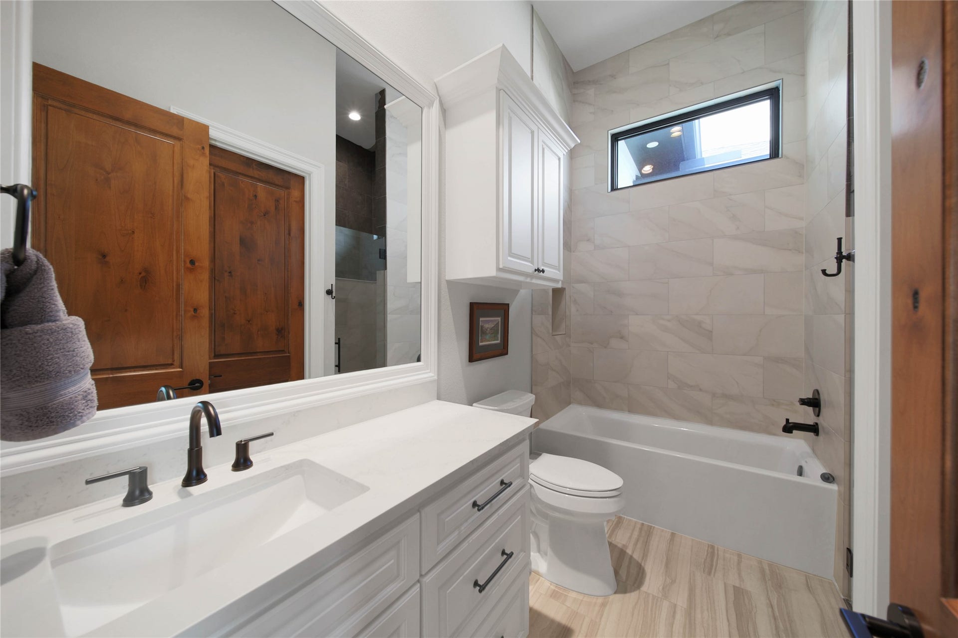 24718 Shadow Pond Drive, Spring, TX 77389 Elegant bathroom featuring a sleek double vanity with modern fixtures, a spacious tub with tiled surround, and warm wooden accents for a cozy touch.