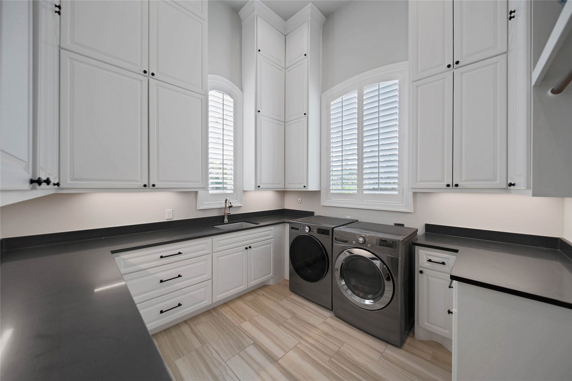 24718 Shadow Pond Drive, Spring, TX 77389 Elegant laundry room with ample white cabinetry, sleek countertops, and modern appliances, enhanced by large windows for natural light.