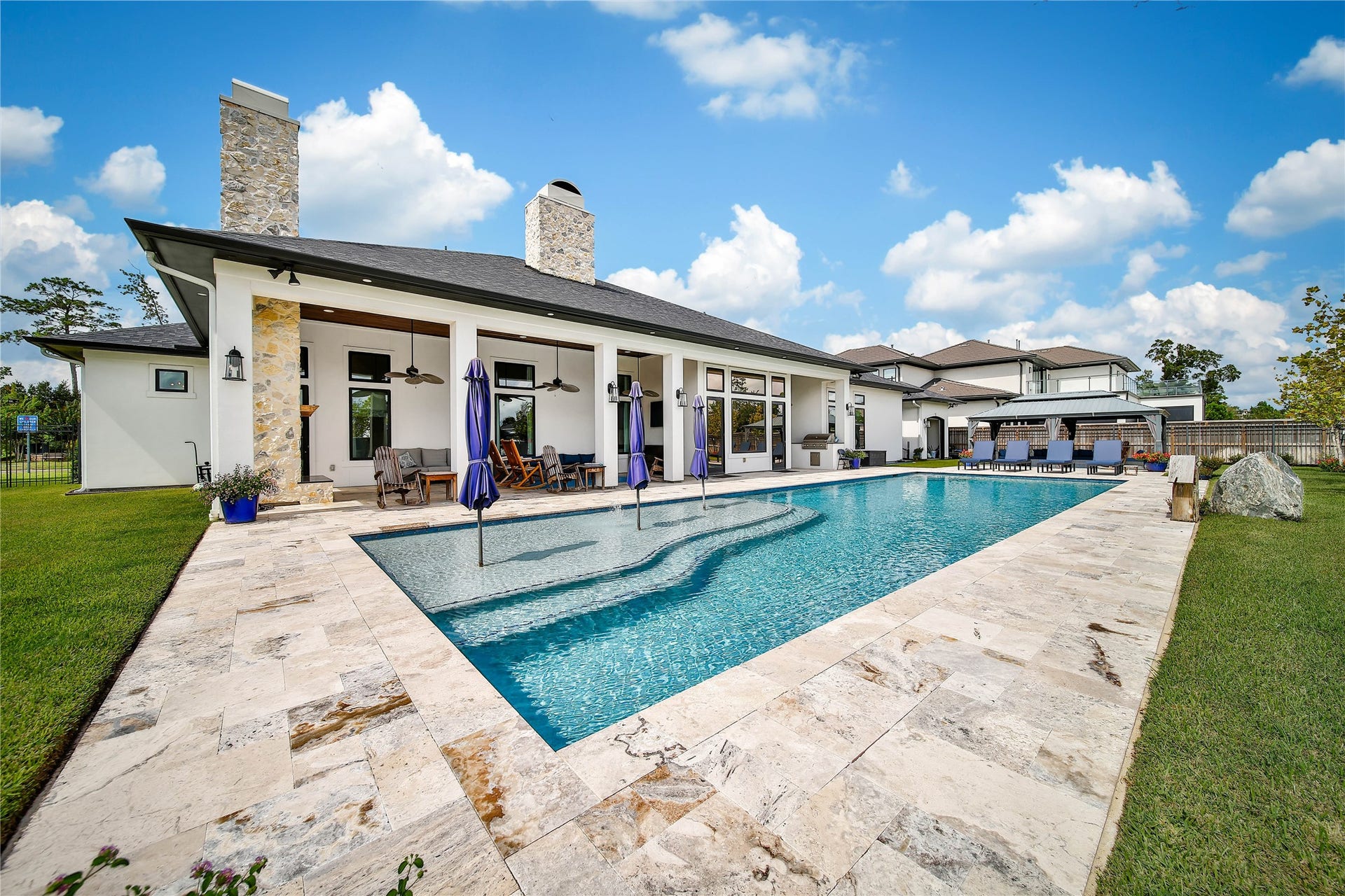 24718 Shadow Pond Drive, Spring, TX 77389 Stunning modern home with expansive outdoor living space, featuring a sleek pool and elegant stone patio, perfect for entertaining and relaxation.