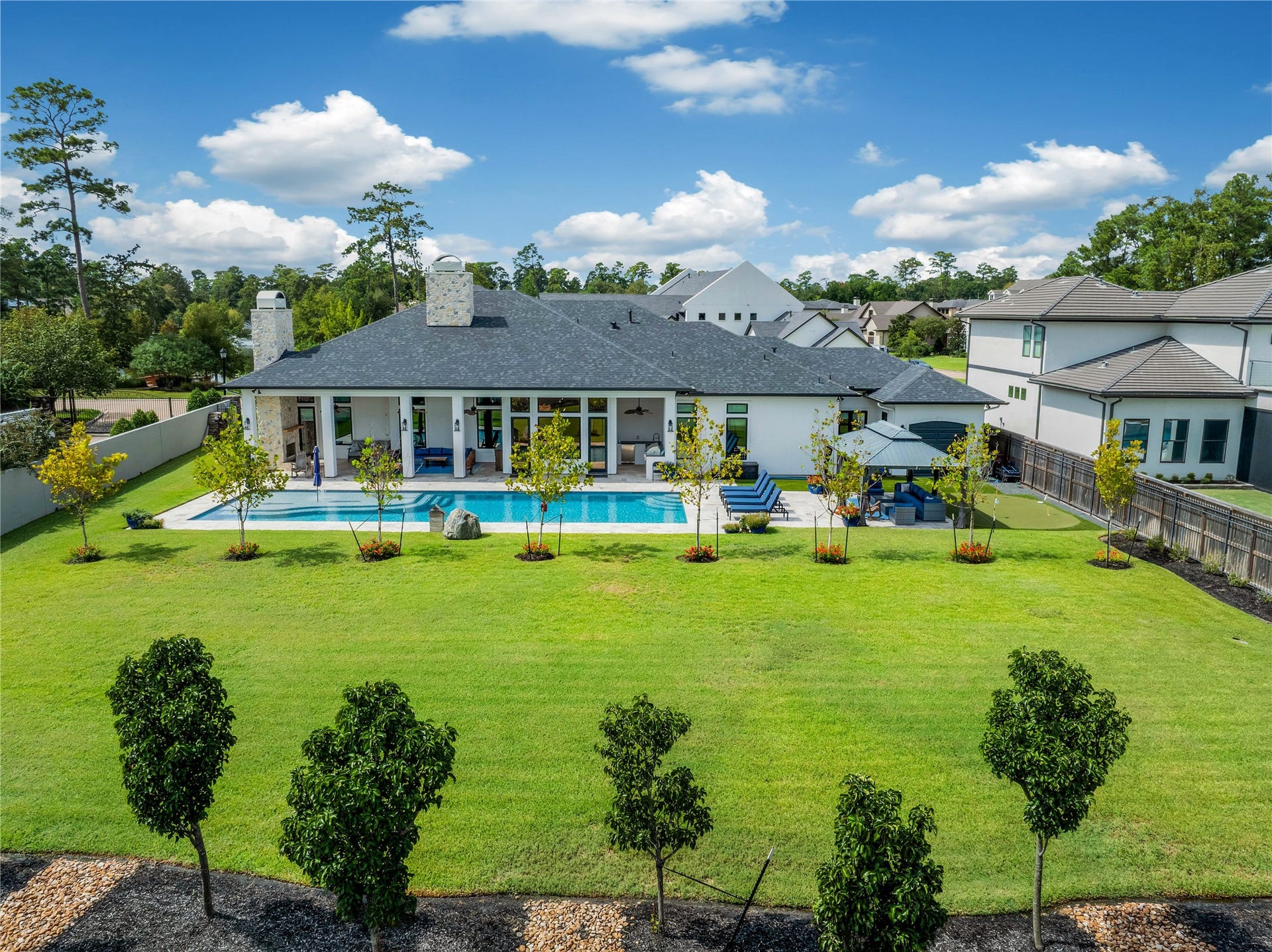 24718 Shadow Pond Drive, Spring, TX 77389 Luxurious home with a spacious backyard featuring a stunning pool, lush landscaping, and a covered patio, perfect for outdoor gatherings and relaxation.
