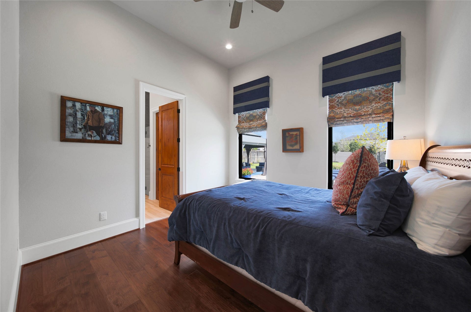 24718 Shadow Pond Drive, Spring, TX 77389 Cozy bedroom with hardwood floors, a stylish wood door, and large windows adorned with elegant blinds, offering ample natural light.