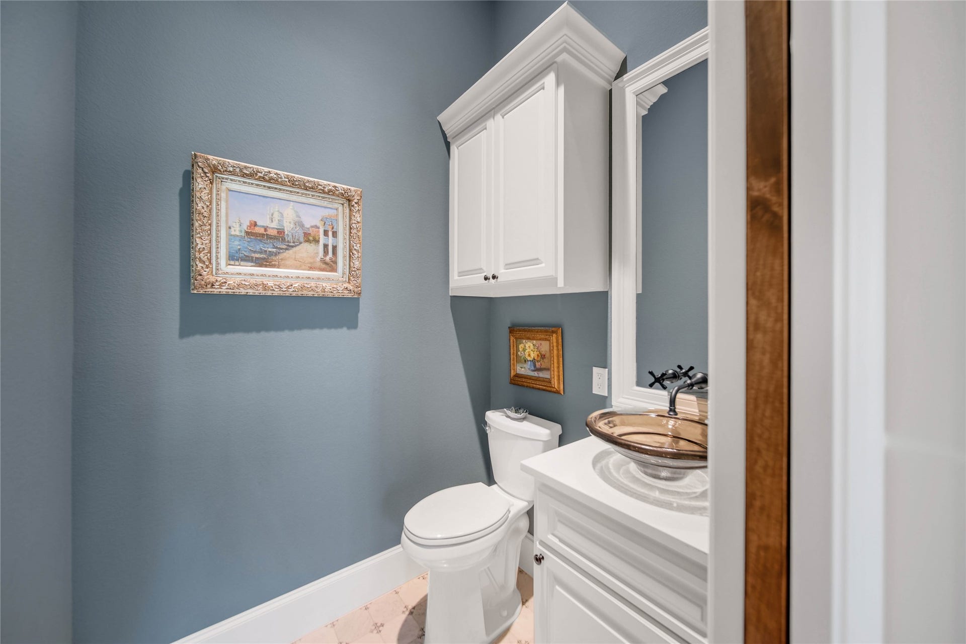 24718 Shadow Pond Drive, Spring, TX 77389 Charming powder room featuring elegant blue walls, white cabinetry, and tasteful artwork, offering a sophisticated and cozy ambiance.