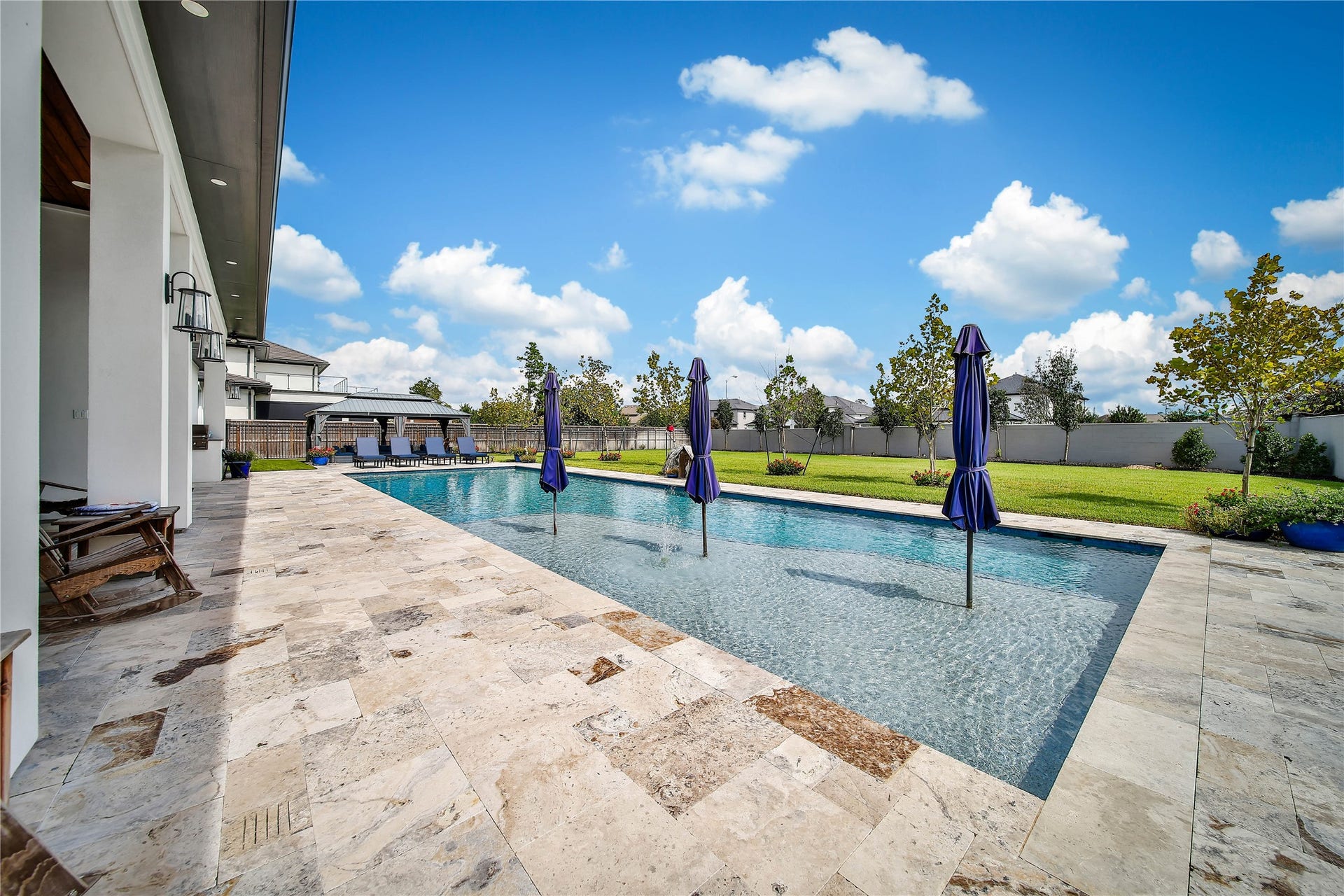 24718 Shadow Pond Drive, Spring, TX 77389 Luxurious outdoor oasis featuring a sparkling pool with elegant stone decking, surrounded by lush landscaping and ample space for relaxation and entertainment.
