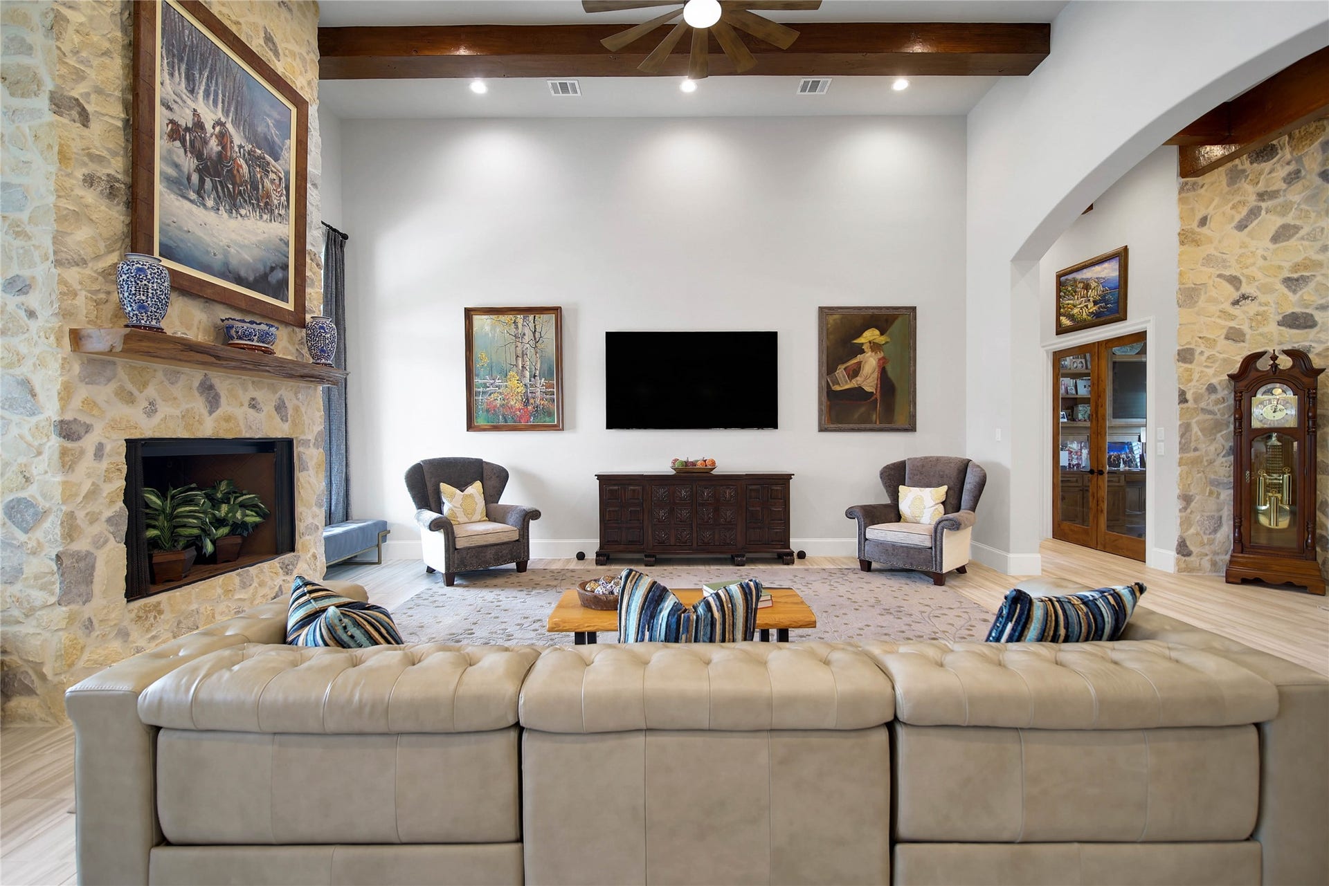 24718 Shadow Pond Drive, Spring, TX 77389 Spacious living room with high ceilings features a stone fireplace, elegant artwork, and stylish seating, creating a cozy yet sophisticated atmosphere.