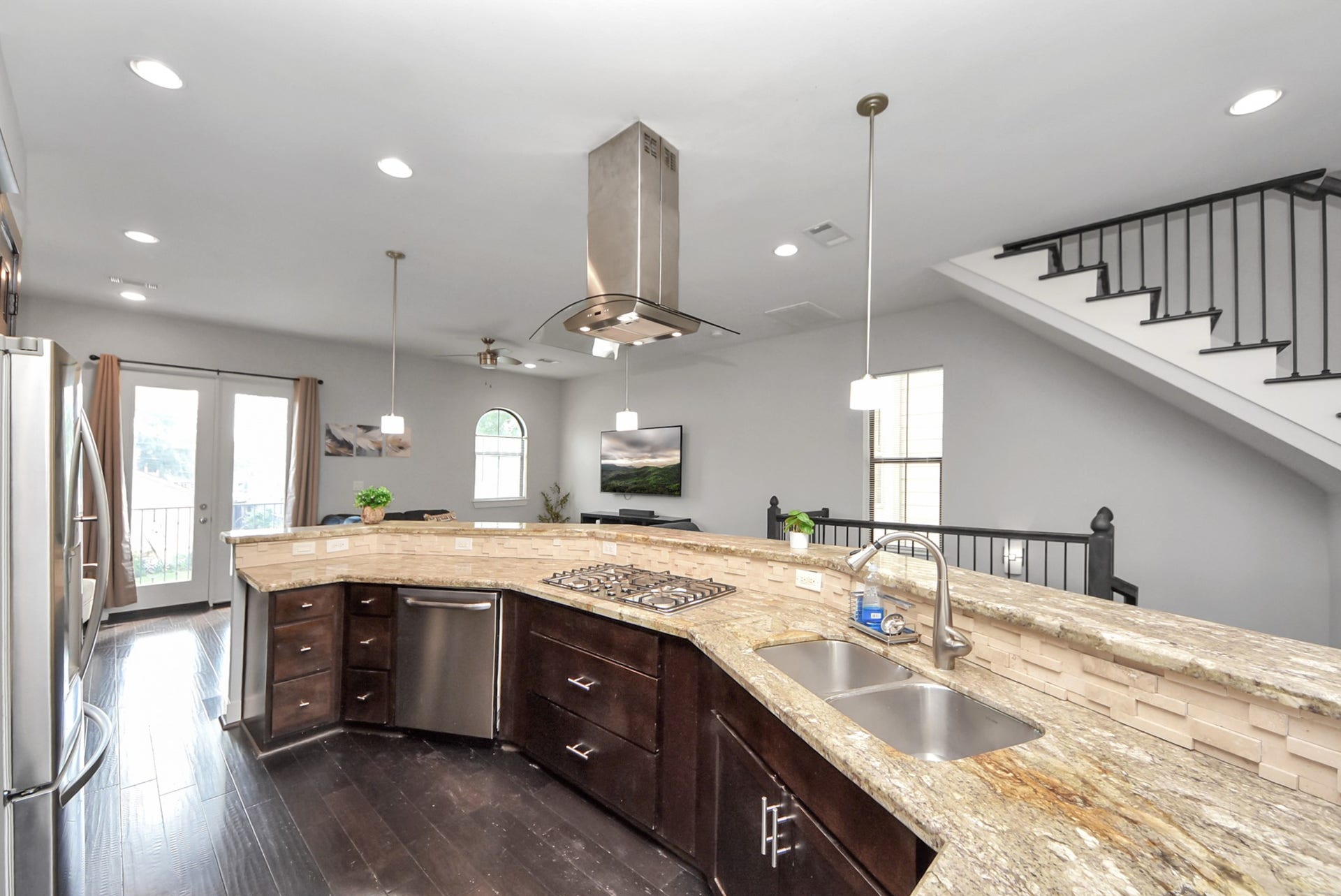 1706 Spring Street, Houston, TX 77007 Well-appointed kitchen with granite countertops, dark cabinetry, stainless steel appliances, gas cooktop, and contemporary vent hood.