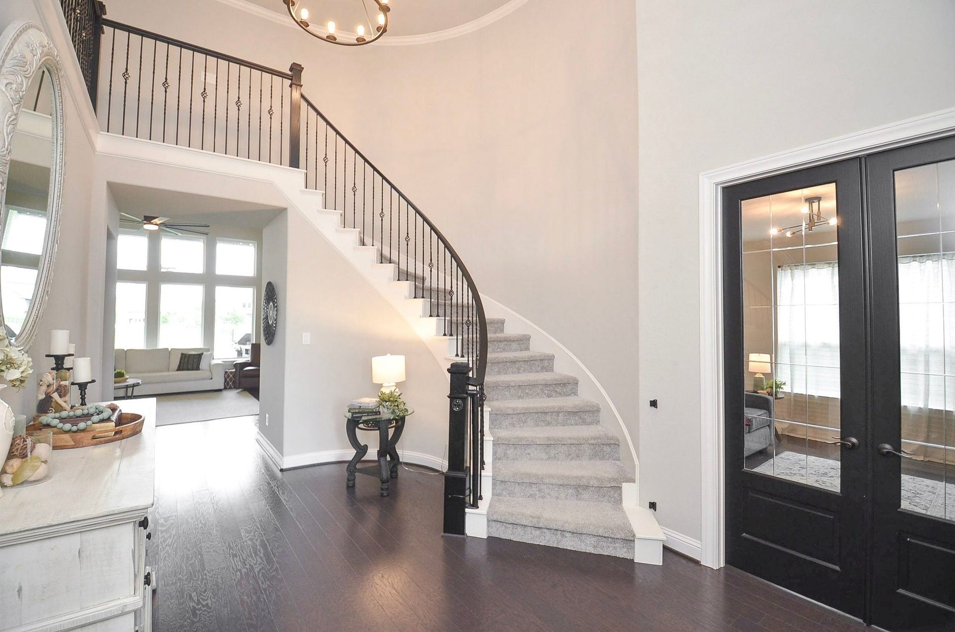 Your grand foyer - the perfect spot to showcase your Christmas tree, where soaring ceilings, natural light, modern chandelier and an elegant curved staircase with wrought-iron detailing create a stunning first impression.
